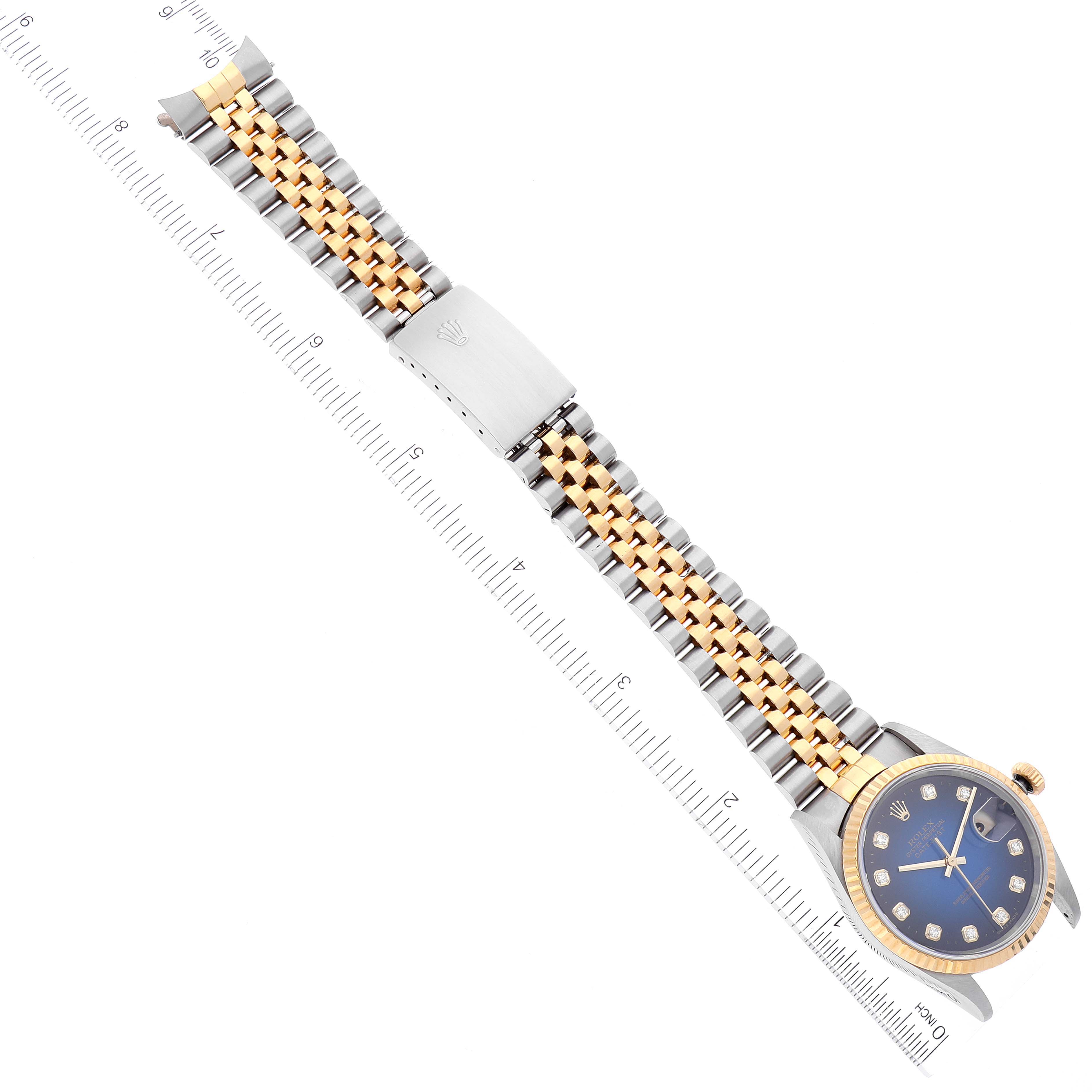 The Rolex Datejust 16233 Men's Steel and Gold (two tone) Blue Dial 16233 Men's Steel and Gold (two tone) Blue Dial watch is shown from a top view, displaying its face, two-tone bracelet, and a measurement ruler for scale.