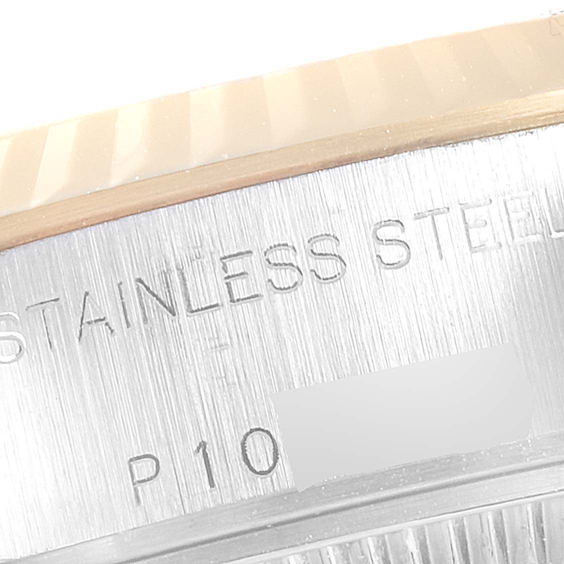 This image shows a close-up view of the side of a Rolex Datejust 79173 Women's Steel and Gold (two tone) Champagne Dial 79173 Women's Steel and Gold (two tone) Champagne Dial, featuring the fluted bezel and engraved text on its stainless steel case.