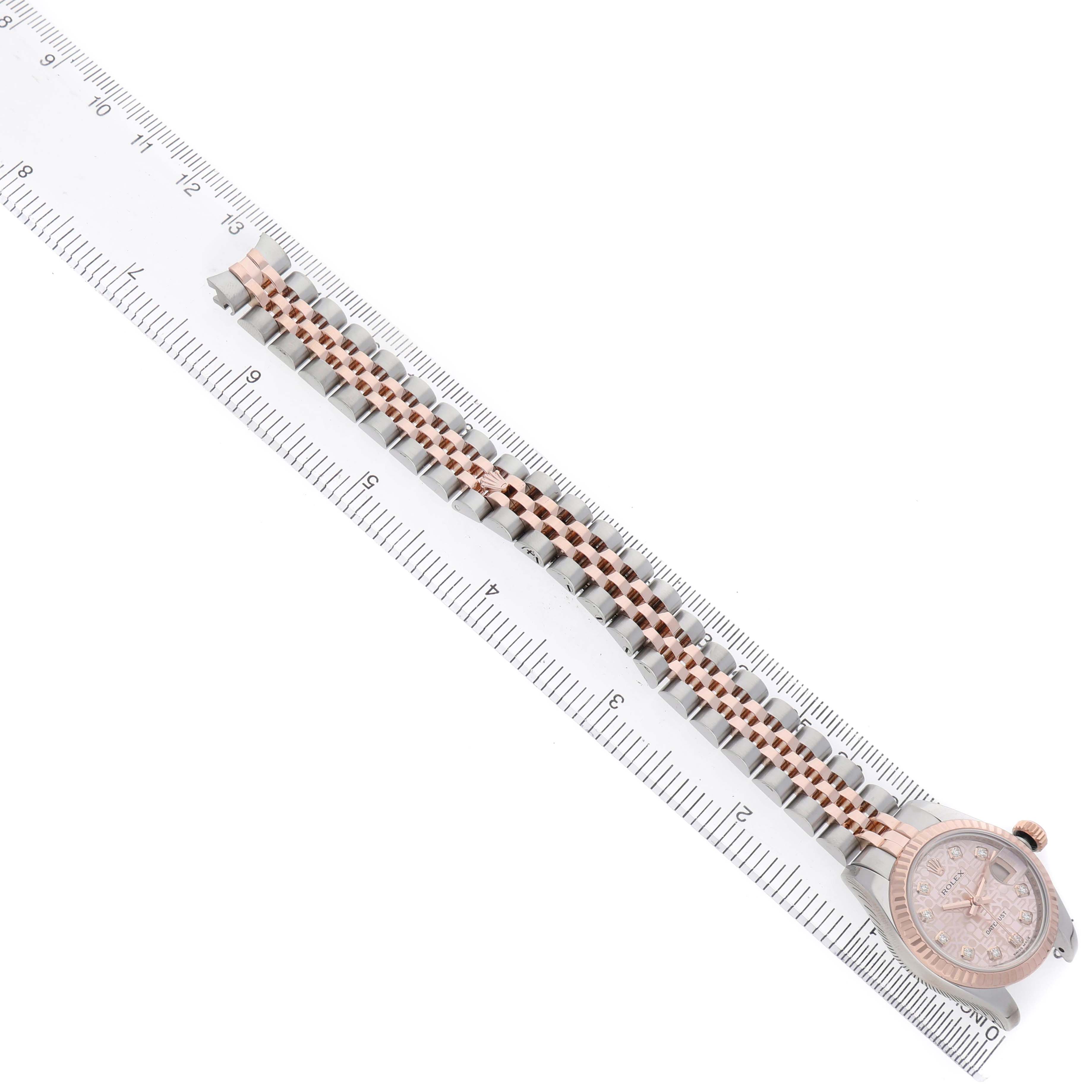 The Rolex Datejust 179171 Women's Stainless Steel Pink Dial watch is shown from a top-down angle with its bracelet fully extended alongside a ruler.