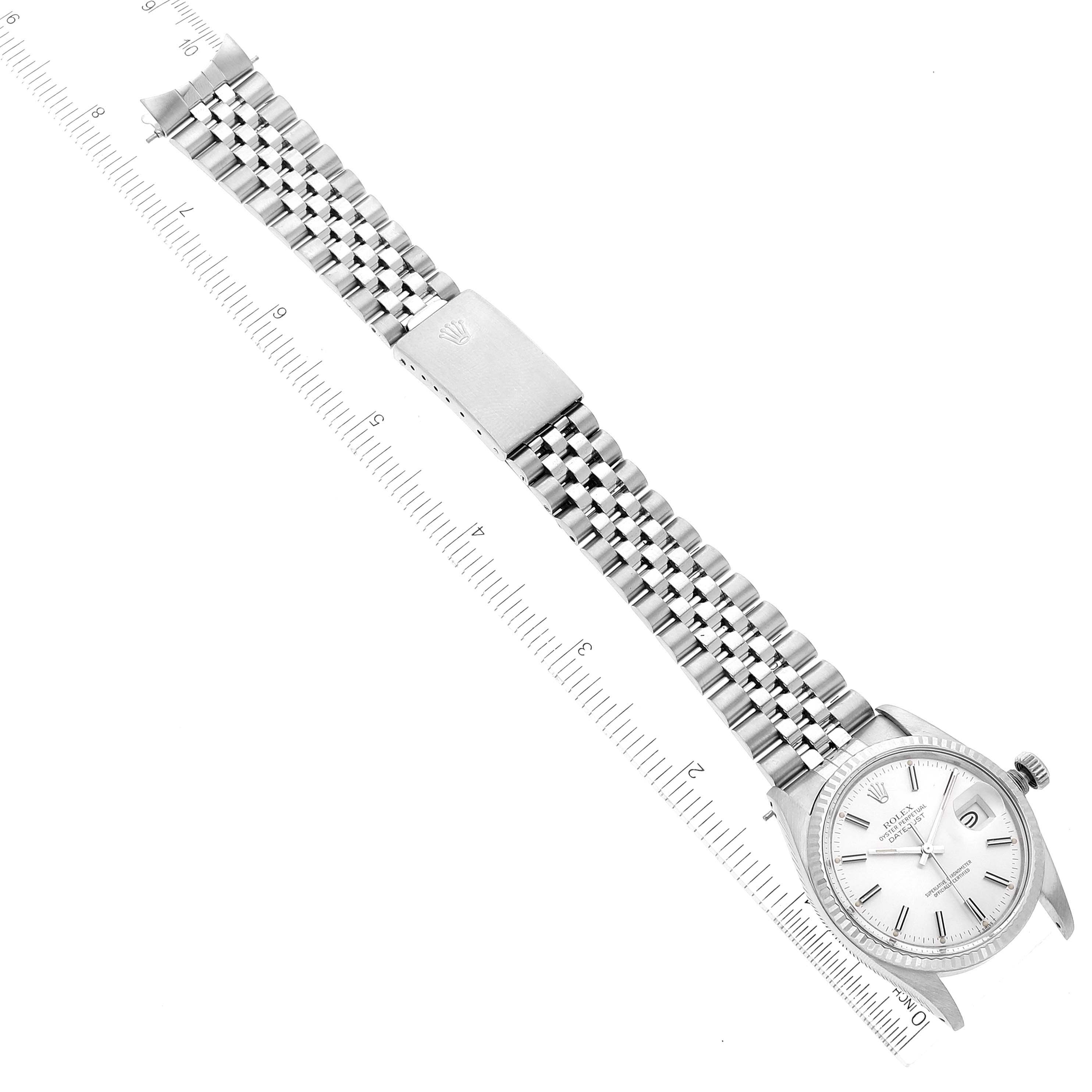 The Rolex Datejust 16014 Men
s Stainless Steel Silver Dial 16014 Men
s Stainless Steel Silver Dial watch is shown in a top-down view, highlighting the face, bracelet, and clasp alongside a ruler for scale.