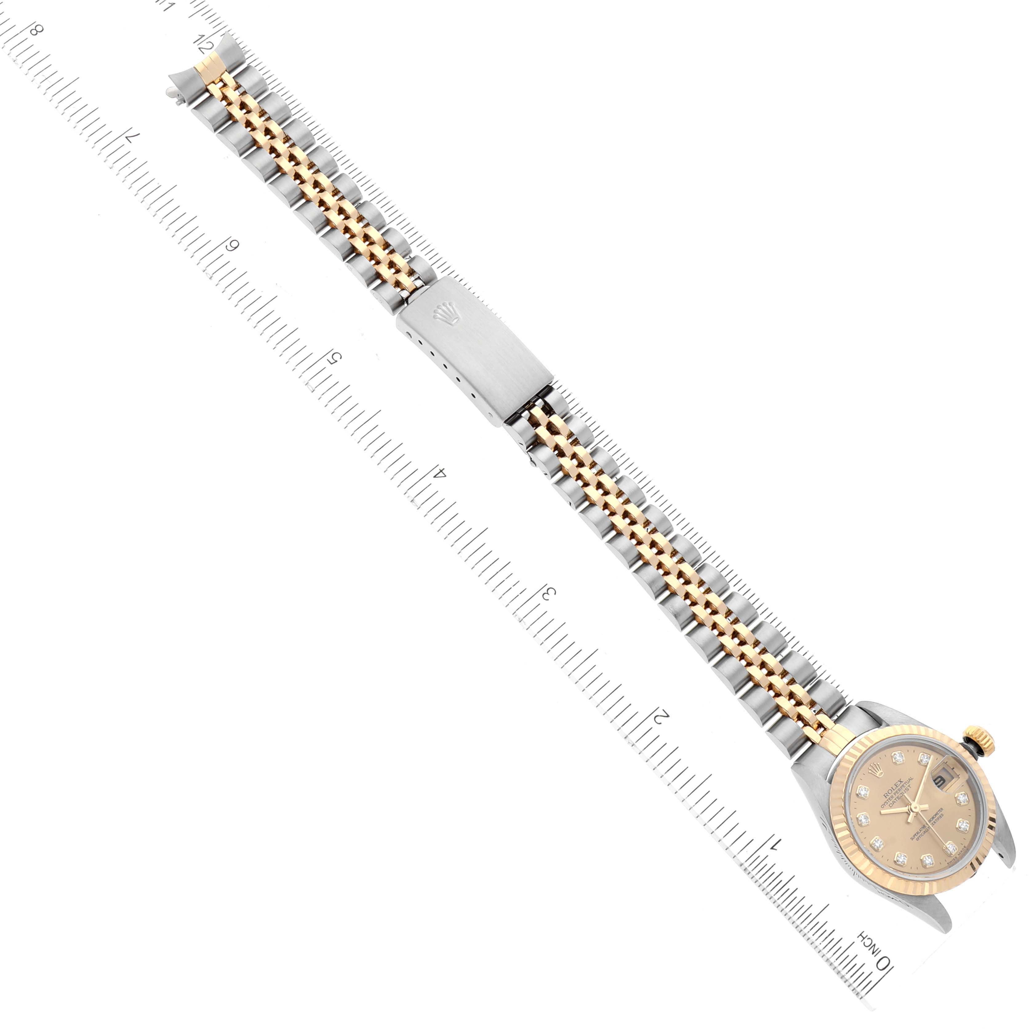 The Rolex Datejust 79173 Women's Steel and Gold (two tone) Champagne Dial 79173 Women's Steel and Gold (two tone) Champagne Dial watch is shown flat with its full length, including the face, bracelet, and clasp, aligned alongside a ruler.