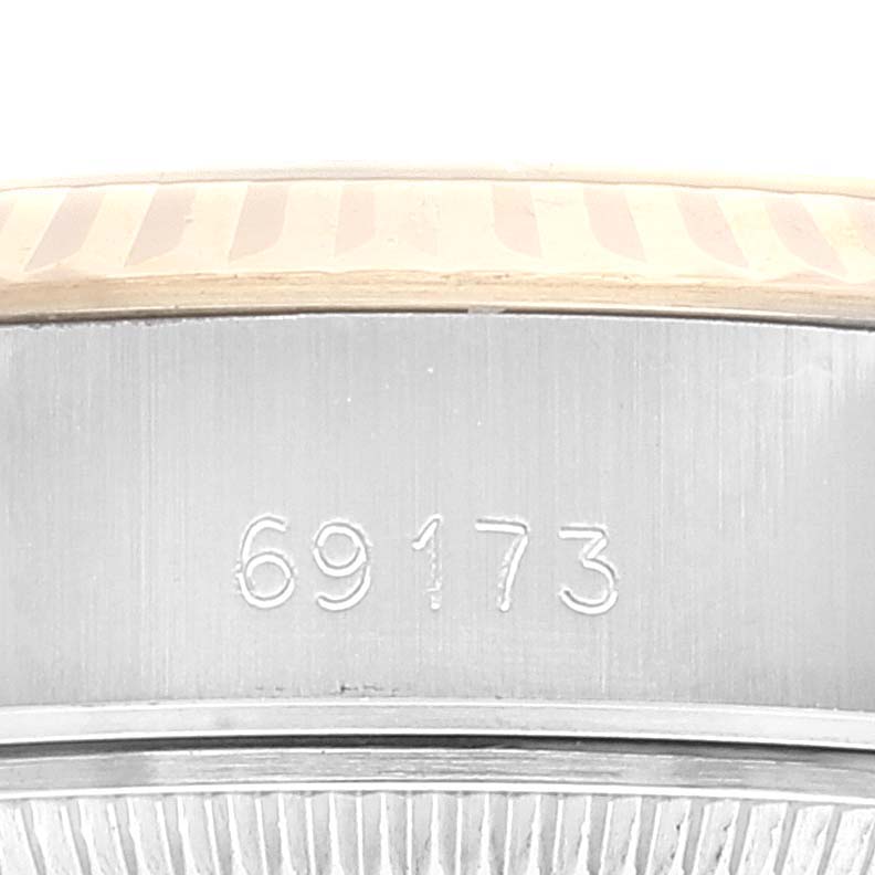 A close-up shot of the serial number on a Rolex Datejust 69173 Women
s Steel and Gold (two tone) Black Dial 69173 Women
s Steel and Gold (two tone) Black Dial watch case, showing part of the bezel.