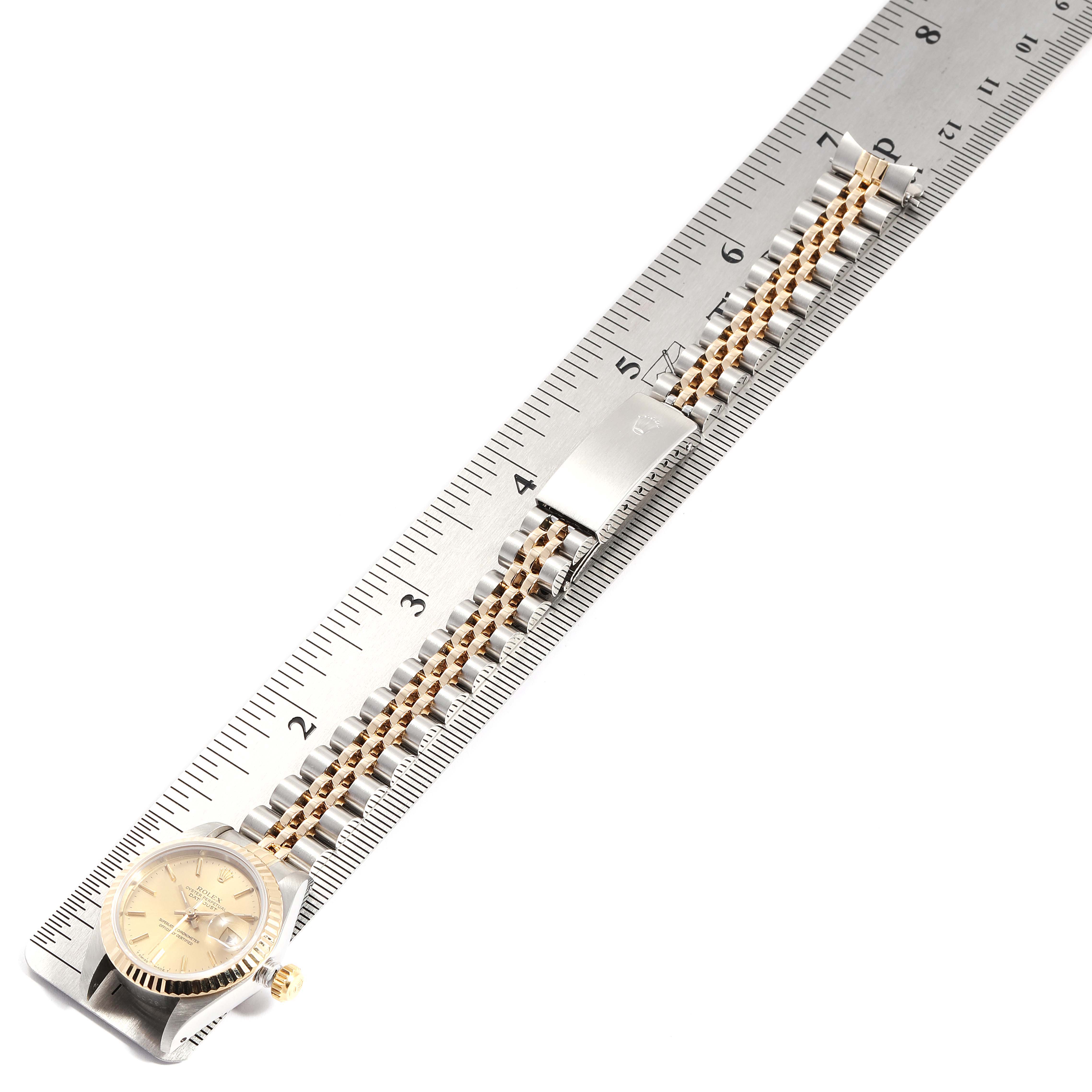 The image shows a Rolex Oyster Perpetual 69173 Women
s Steel and Gold (two tone) Champagne Dial 69173 Women
s Steel and Gold (two tone) Champagne Dial watch, including the face and the band, with a ruler measuring the length of the band.