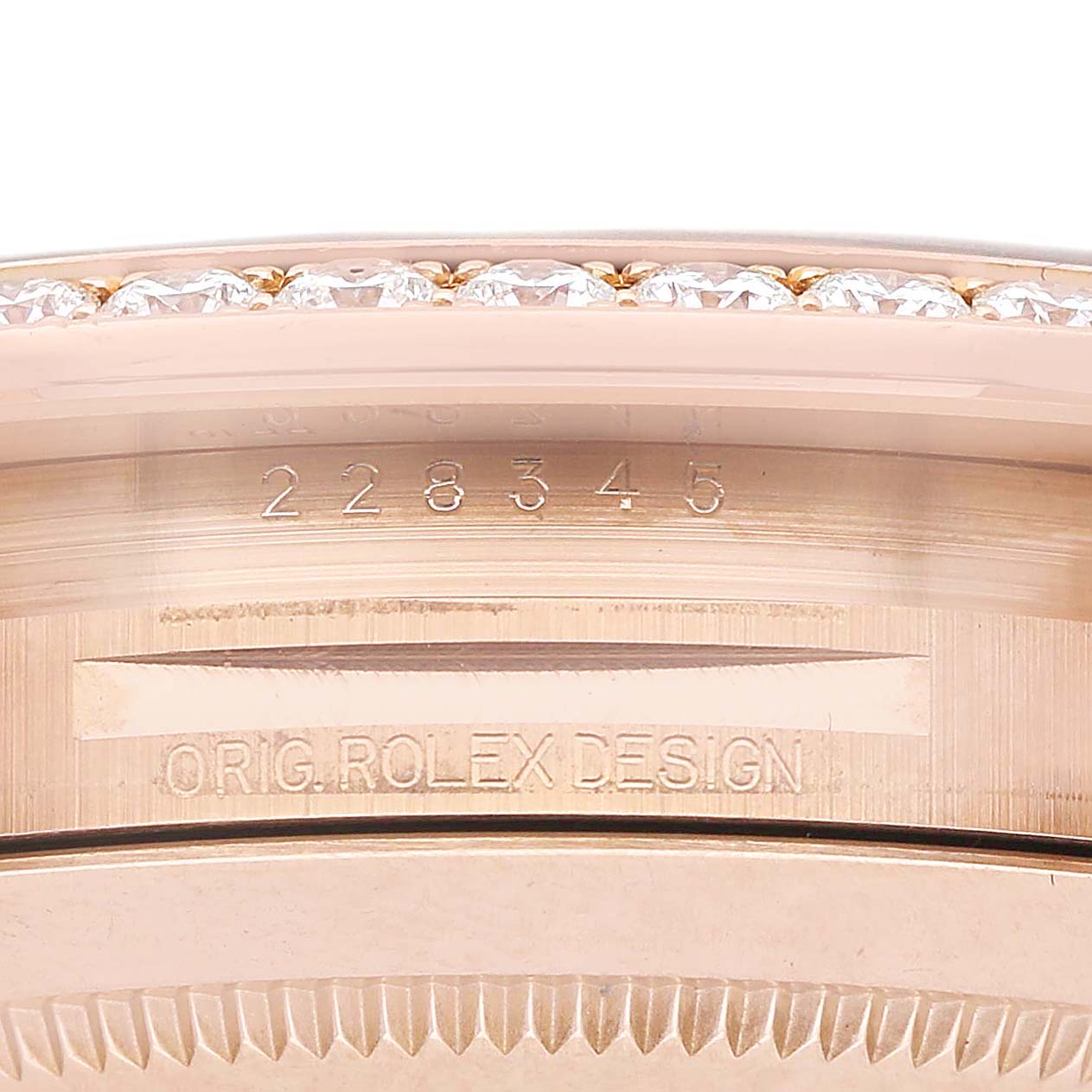 The image shows a close-up side view of a Rolex President 228345 Men's Rose Gold Pink Dial model, highlighting the bezel with diamonds and engraved text.