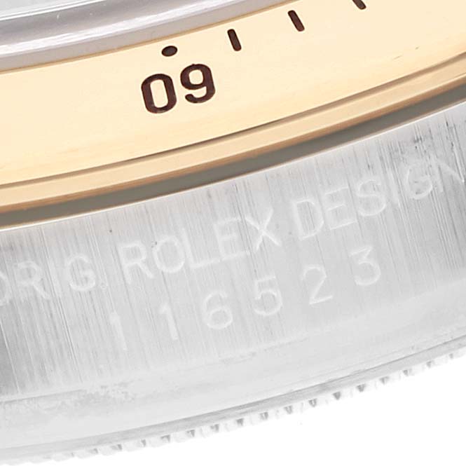 The image shows a close-up of the bezel and engraved edge of a Rolex Daytona 116523 Men's Steel and Gold (two tone) Black Dial 116523 Men's Steel and Gold (two tone) Black Dial watch.