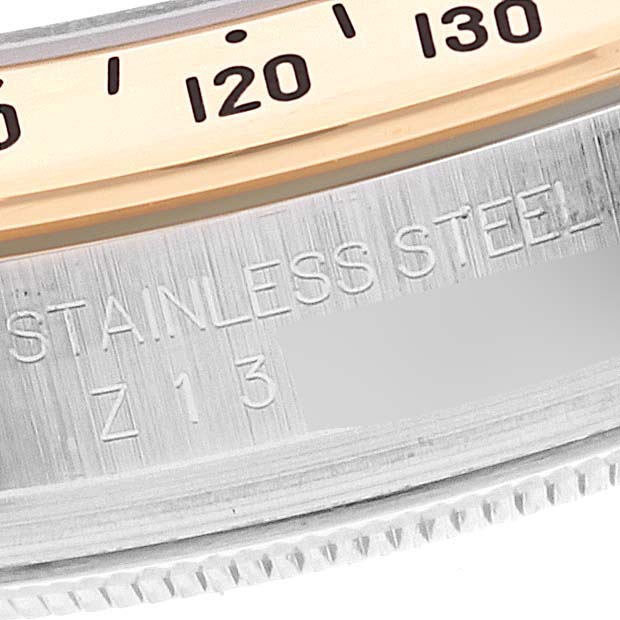 This image shows a close-up of the case and bezel of a Rolex Daytona 116523 Men's Steel and Gold (two tone) Black Dial 116523 Men's Steel and Gold (two tone) Black Dial watch, highlighting the stainless steel material and part of the tachymeter scale.