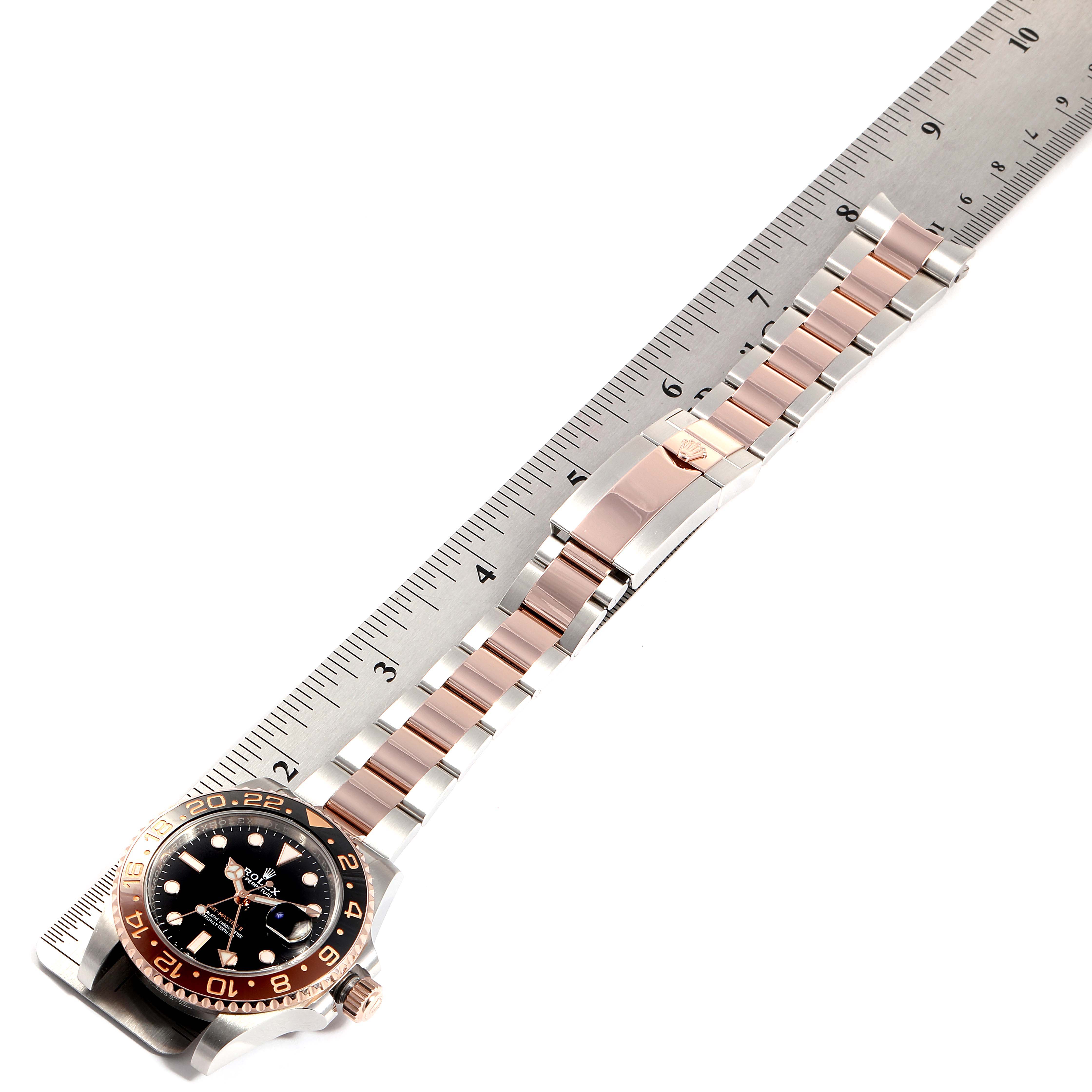The image shows the Rolex GMT-Master 126711 Men's Steel and Gold (two tone) Black Dial 126711 Men's Steel and Gold (two tone) Black Dial watch lying flat with a ruler for scale, highlighting the face, bezel, and bracelet.