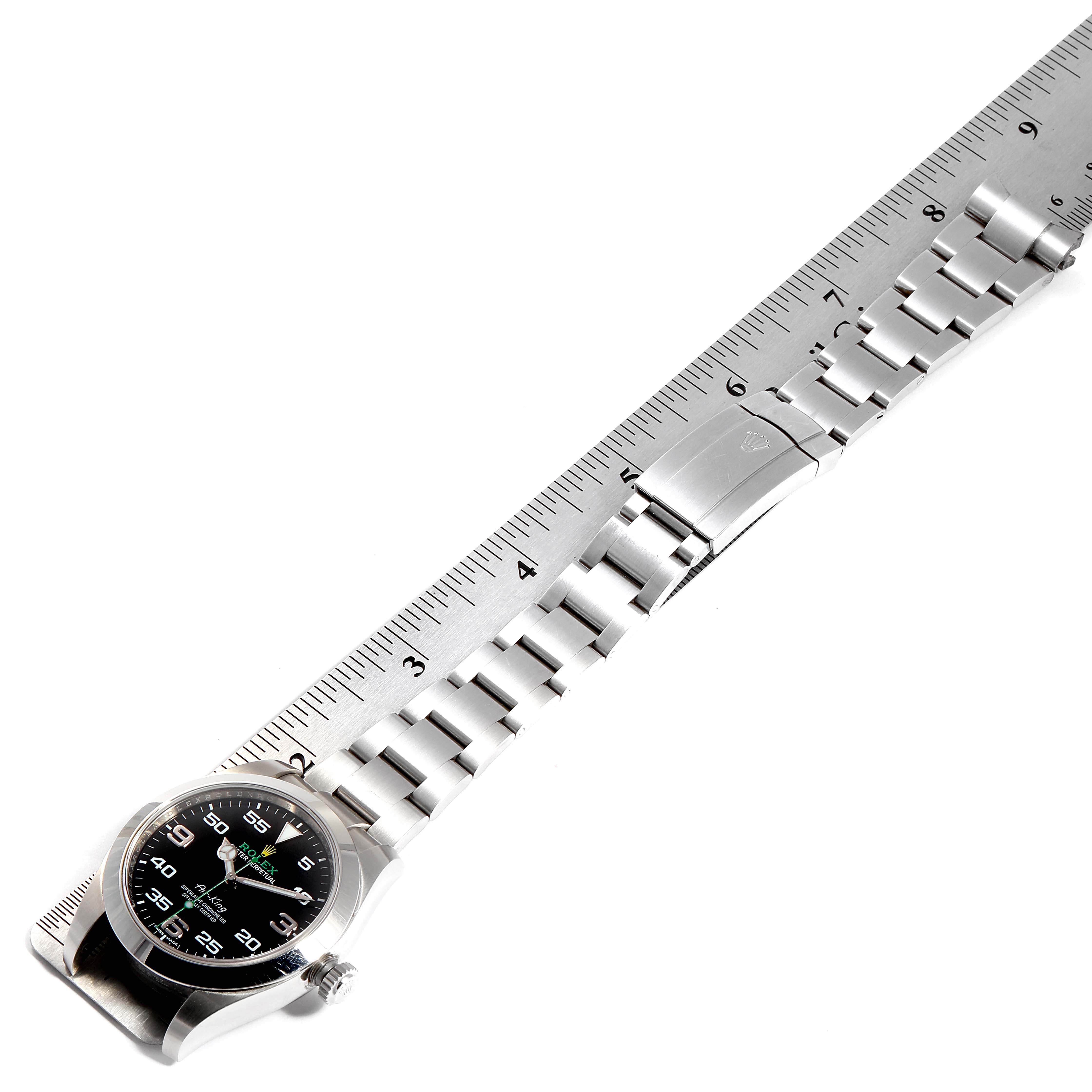 The Rolex Air-King 116900 Men's Stainless Steel Black Dial 116900 Men's Stainless Steel Black Dial watch face and entire bracelet are shown, positioned alongside a measuring ruler.