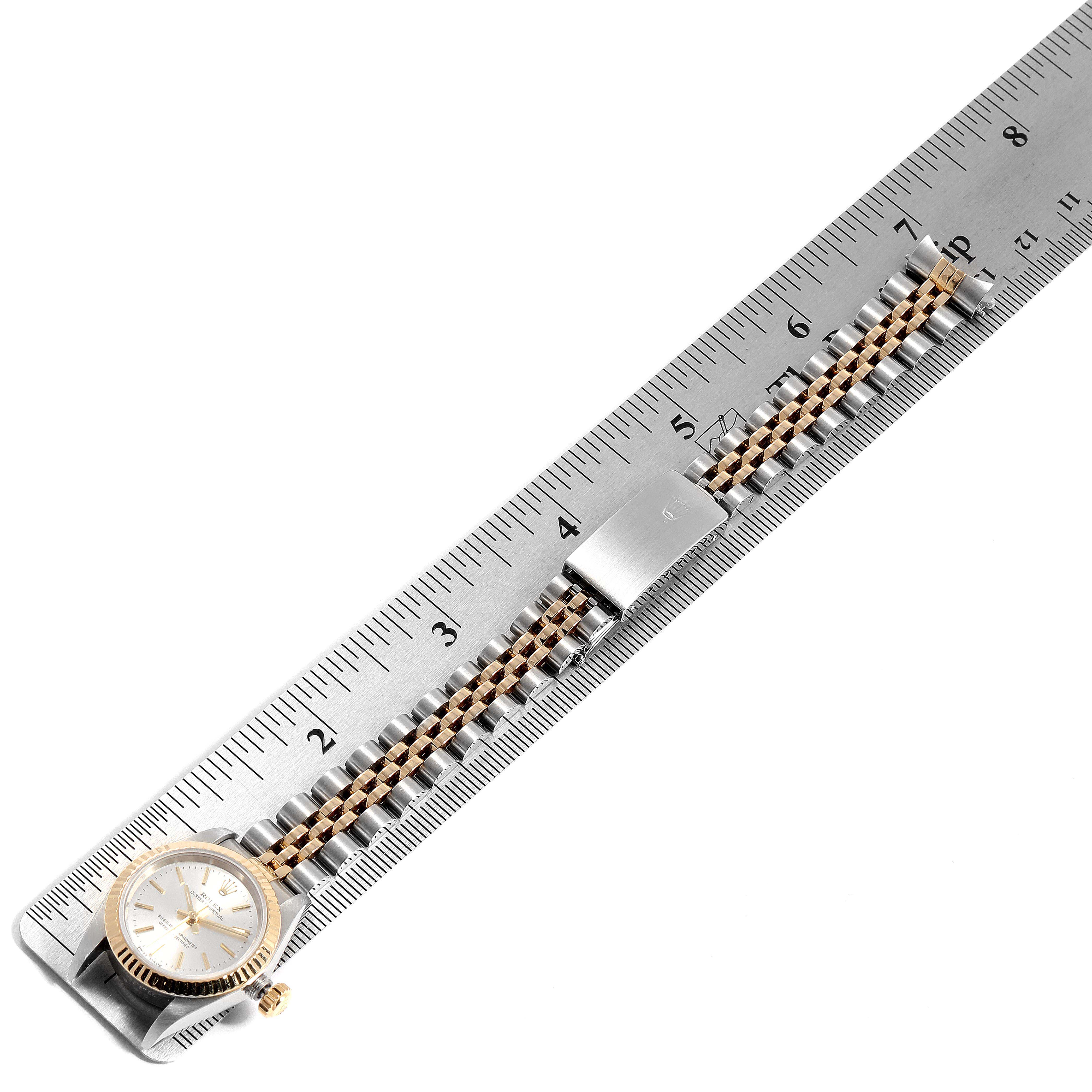 The image shows a Rolex Oyster Perpetual 67193 Women's Steel and Gold (two tone) Silver Dial 67193 Women's Steel and Gold (two tone) Silver Dial watch placed next to a ruler, highlighting the watch band and the face from a top-down angle.