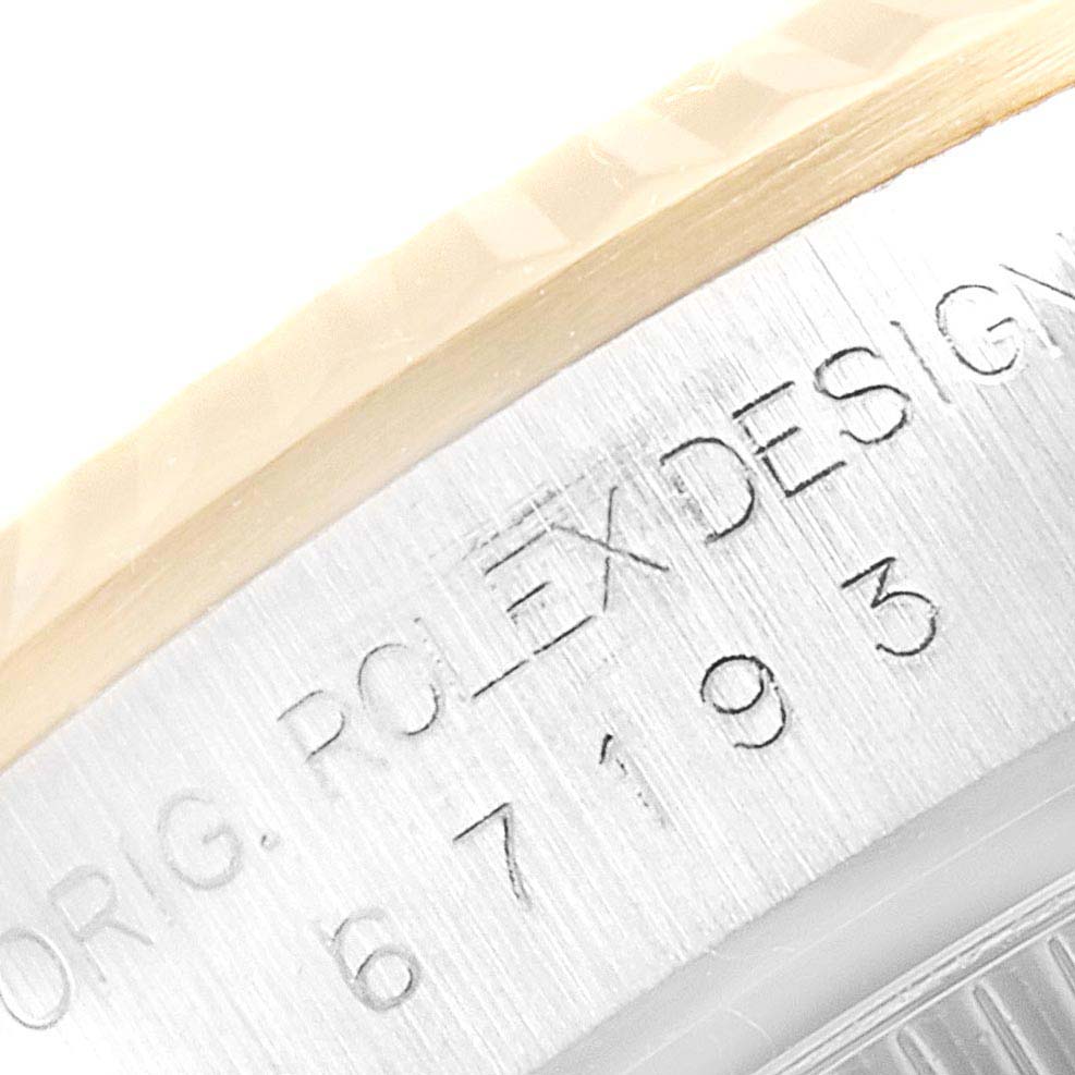 This is a close-up view of the engraved serial number and "Rolex Design" text on the bezel of a Rolex Oyster Perpetual 67193 Women's Steel and Gold (two tone) Silver Dial 67193 Women's Steel and Gold (two tone) Silver Dial watch.