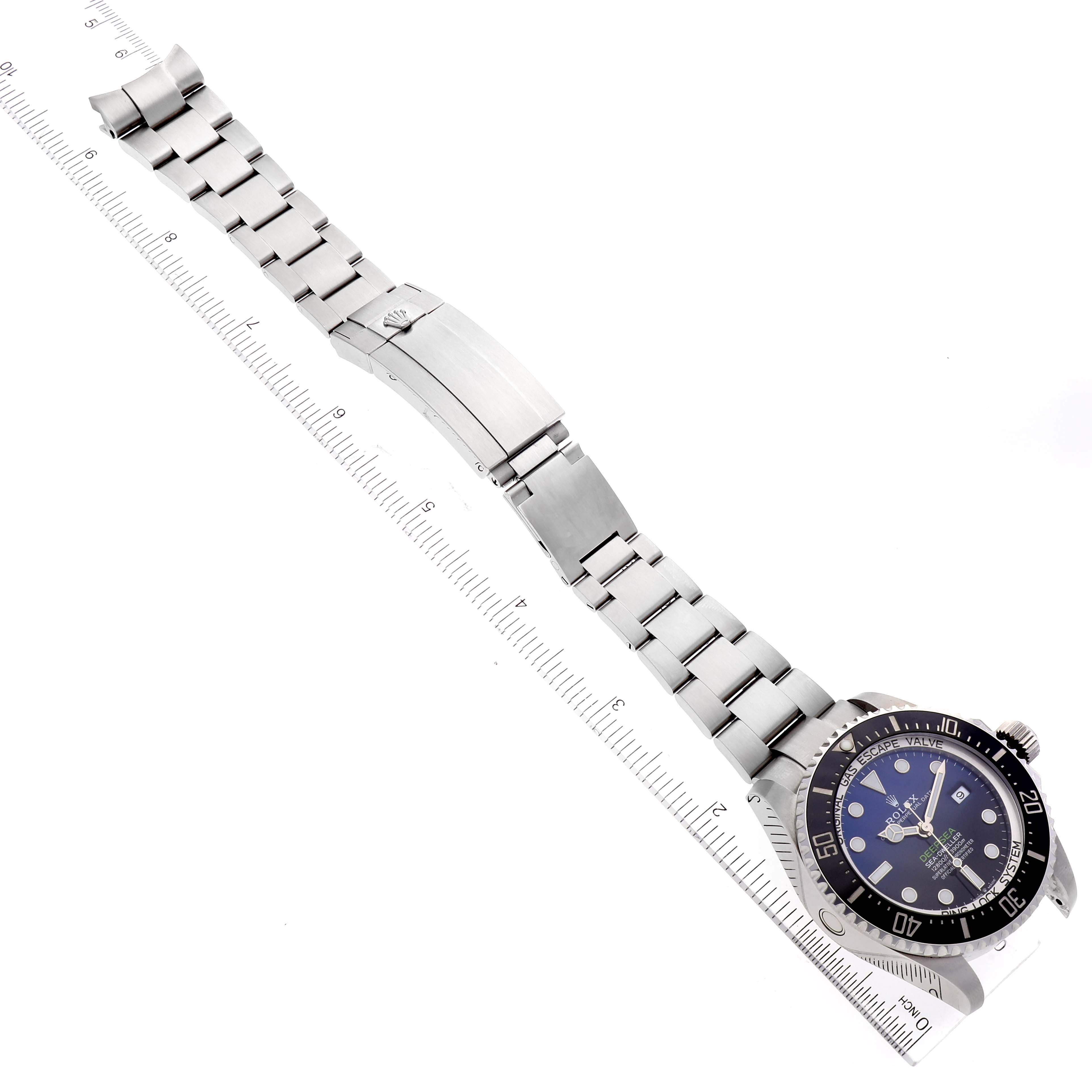 The Rolex Sea-Dweller 126660 Men
s Stainless Steel Blue Dial 126660 Men
s Stainless Steel Blue Dial watch is shown at a diagonal angle, with a visible face, bracelet, and clasp, next to a ruler for scale.