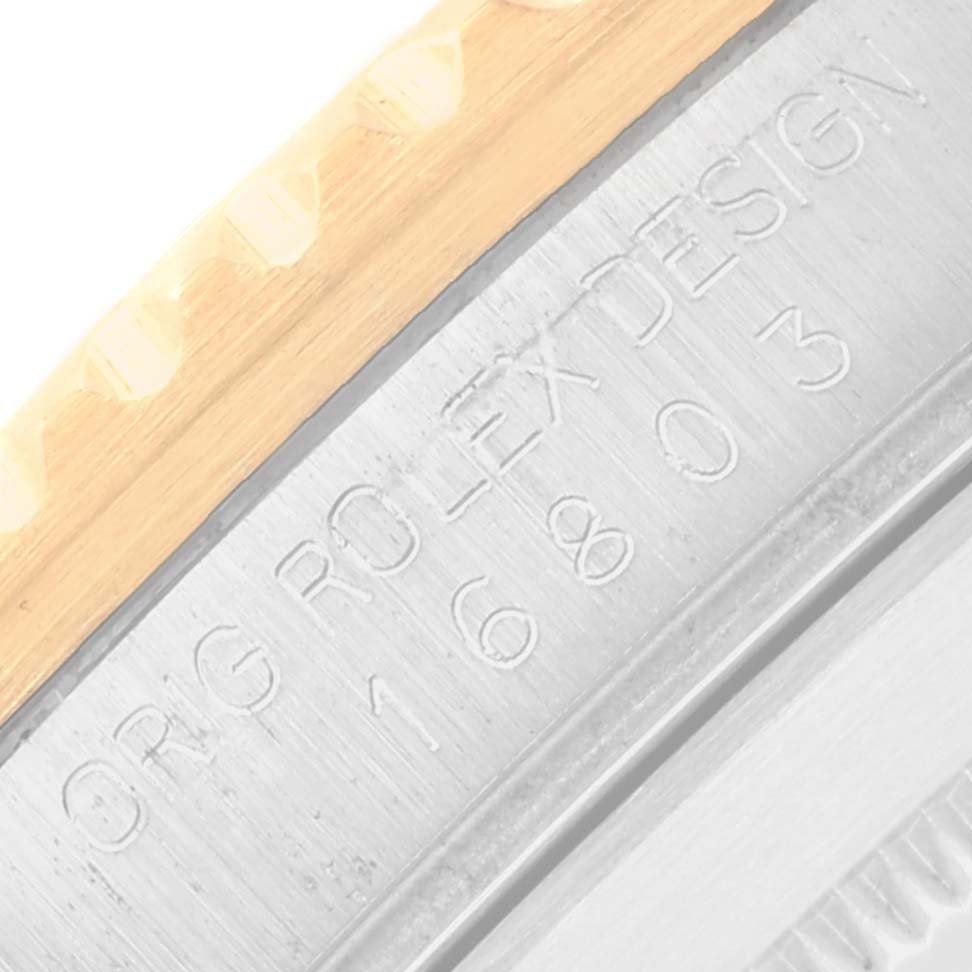 This image shows a close-up of the Rolex Submariner 16803 Men
s Steel and Gold (two tone) Black Dial
s case side, with visible engravings and part of the bezel.