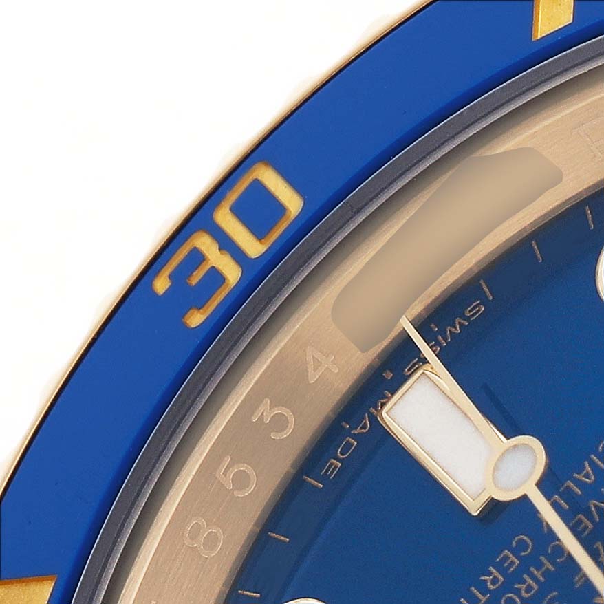 The image shows a close-up of the Rolex Submariner 116618 Men's Yellow Gold Blue Dial's blue bezel and part of the dial with the minute hand.