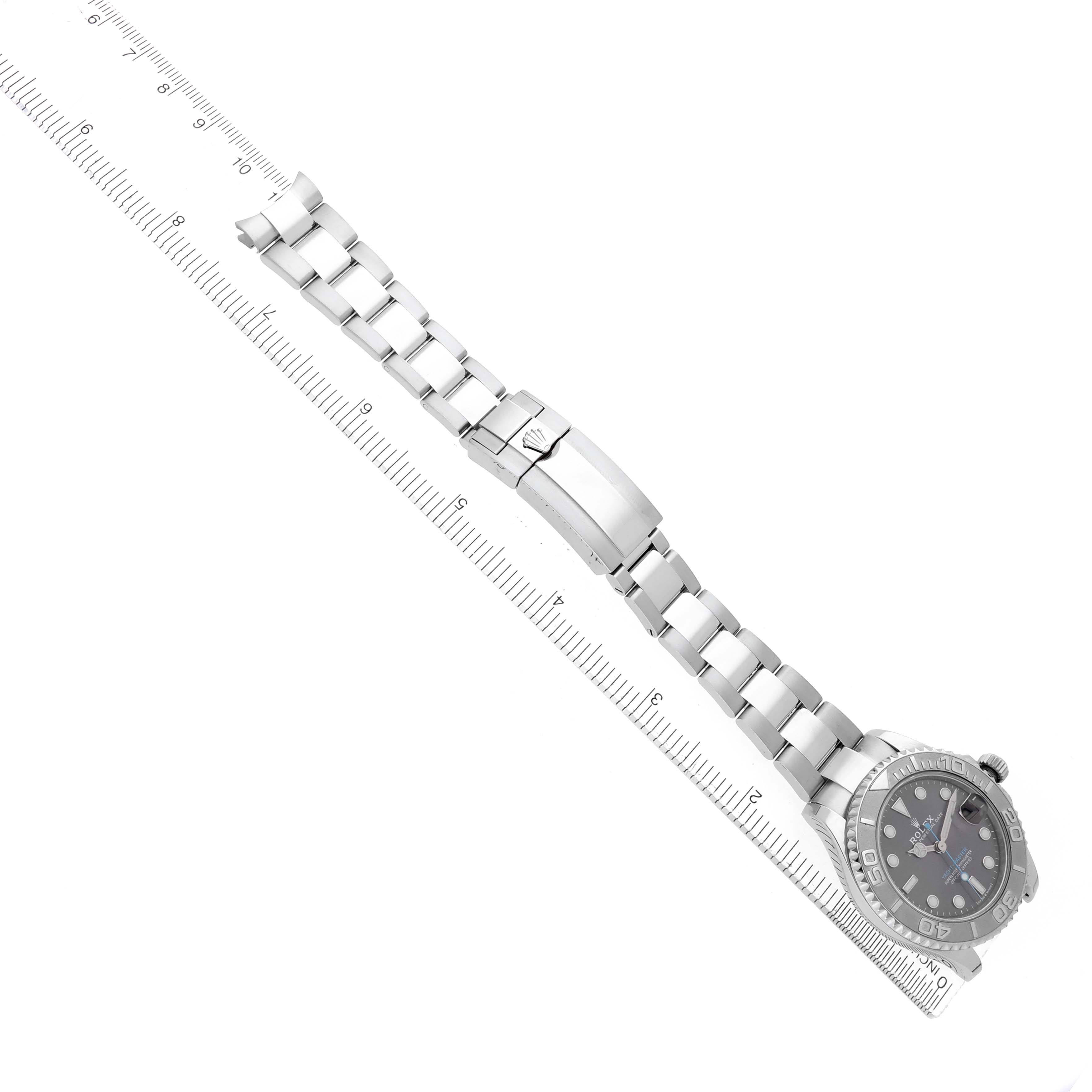 The Rolex Yacht-Master 268622 Men
s Stainless Steel Silver Dial watch is shown flat, featuring the face, bezel, and bracelet alongside a ruler for scale.