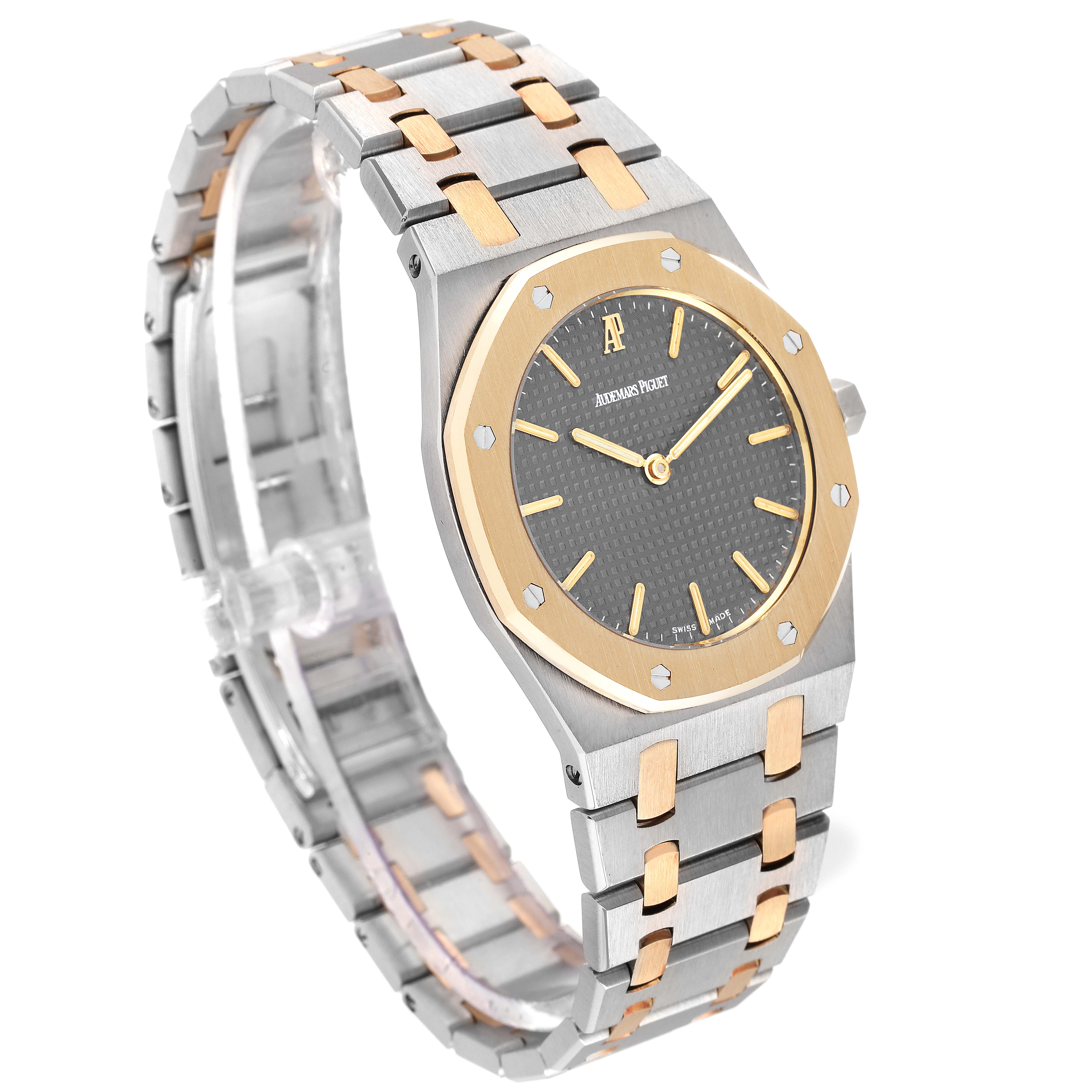The image shows a side angle of a Royal Oak by Audemars Piguet, highlighting the two-tone bracelet and octagonal bezel.