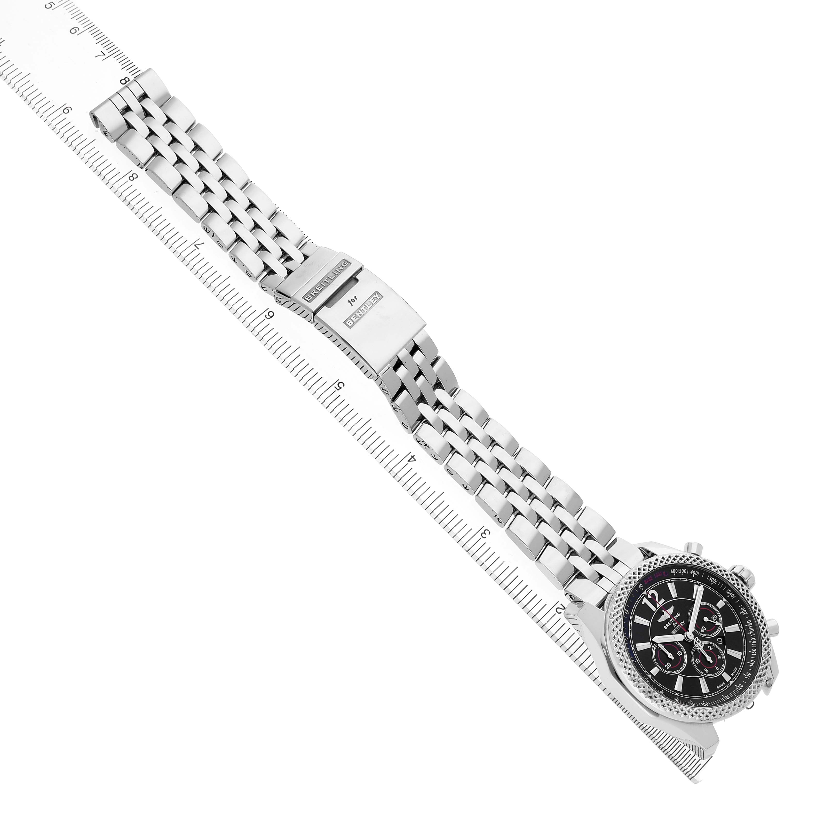 The Breitling Bentley A41390 Men's Stainless Steel Black Dial watch is shown from a top-down angle with its full metal bracelet and clasp visible alongside a ruler for scale.
