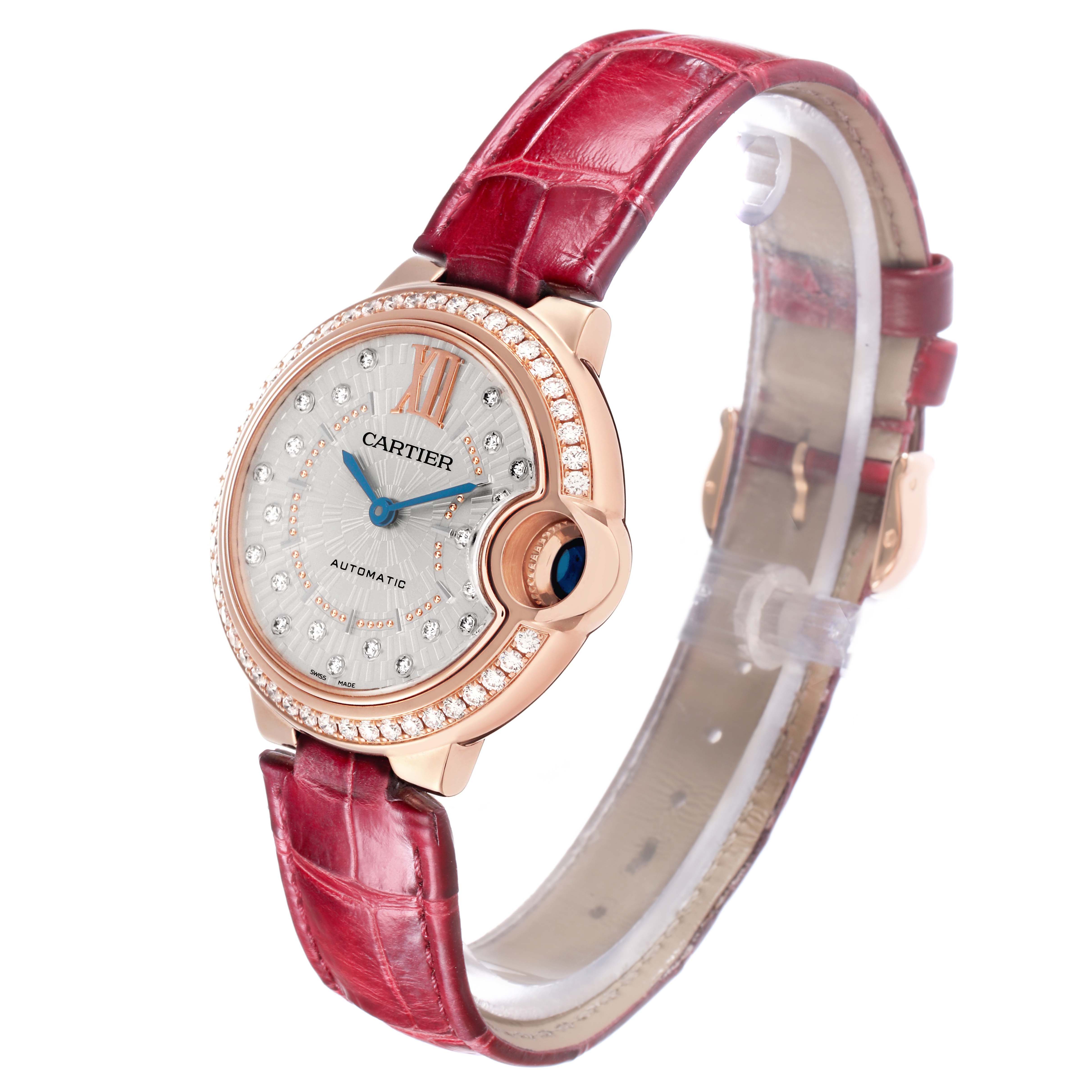 The Cartier Ballon Bleu WJBB0080 Women
s Rose Gold Silver Dial watch is shown at a slight angle, highlighting the face, diamond bezel, and red strap.