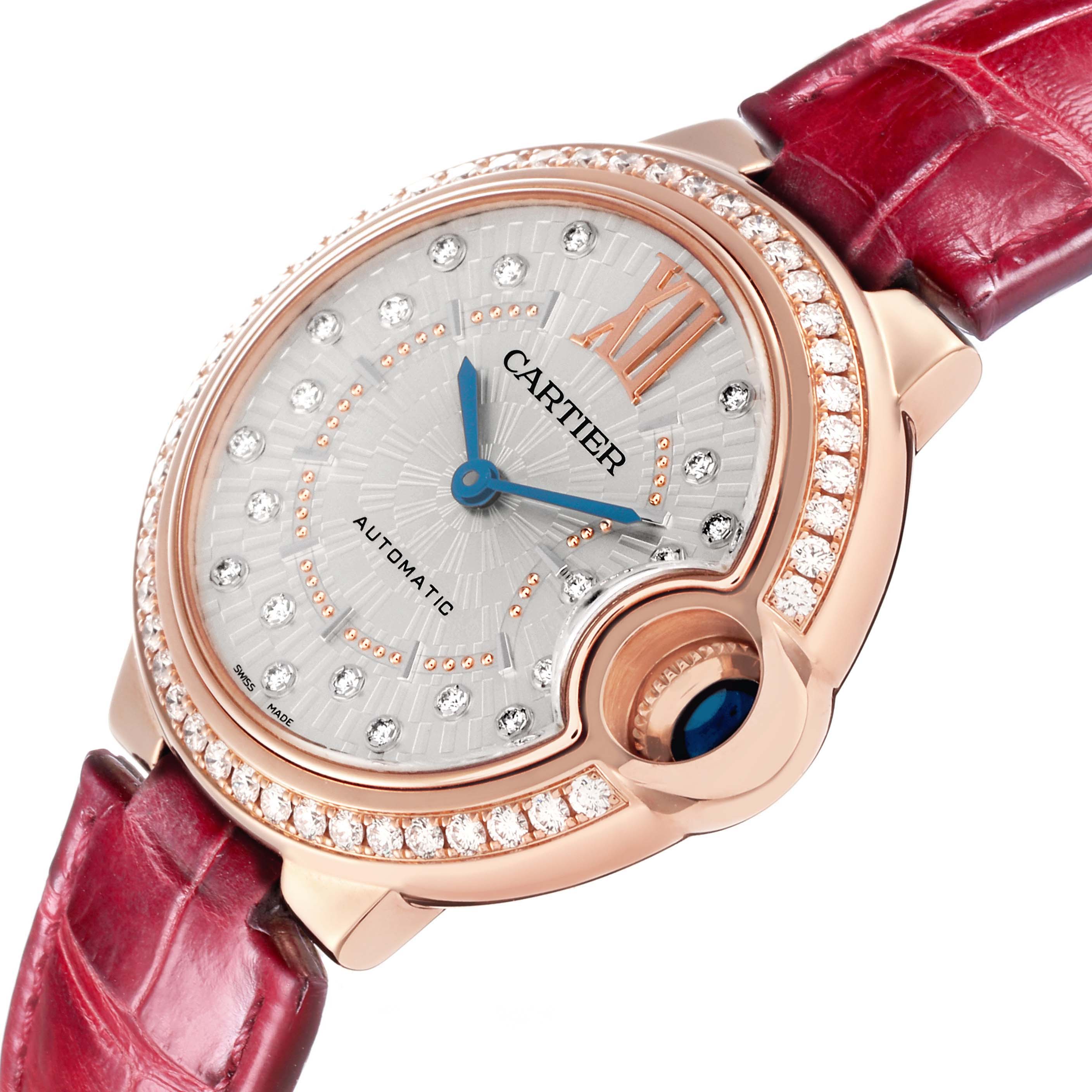 The Cartier Ballon Bleu WJBB0080 Women
s Rose Gold Silver Dial watch is shown at an oblique angle, highlighting the diamond-studded bezel and red leather strap.