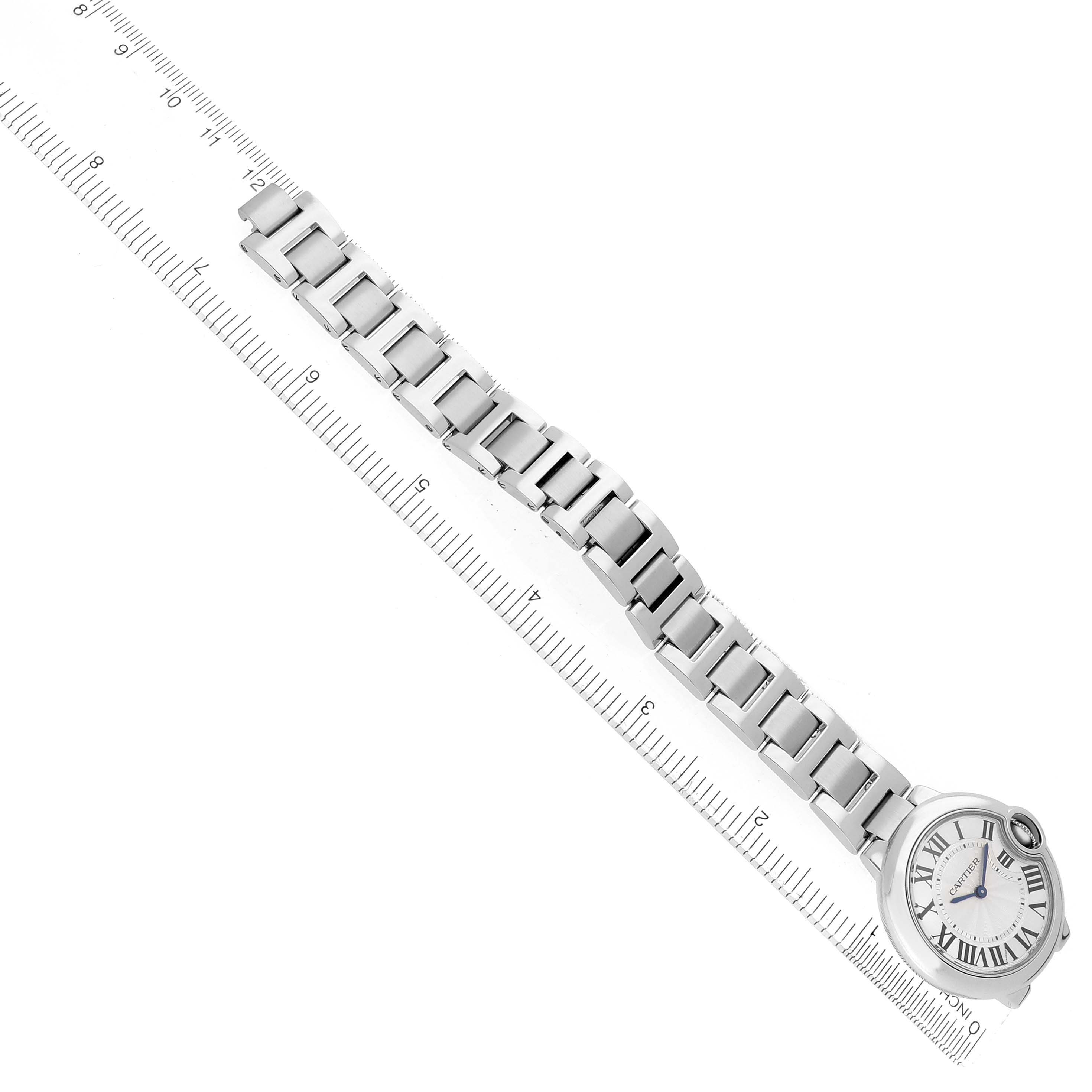 The image shows a top-down angle of the Cartier Ballon Bleu W6920084 Women
s Stainless Steel Silver Dial watch, highlighting its face and metal bracelet alongside a measuring ruler.