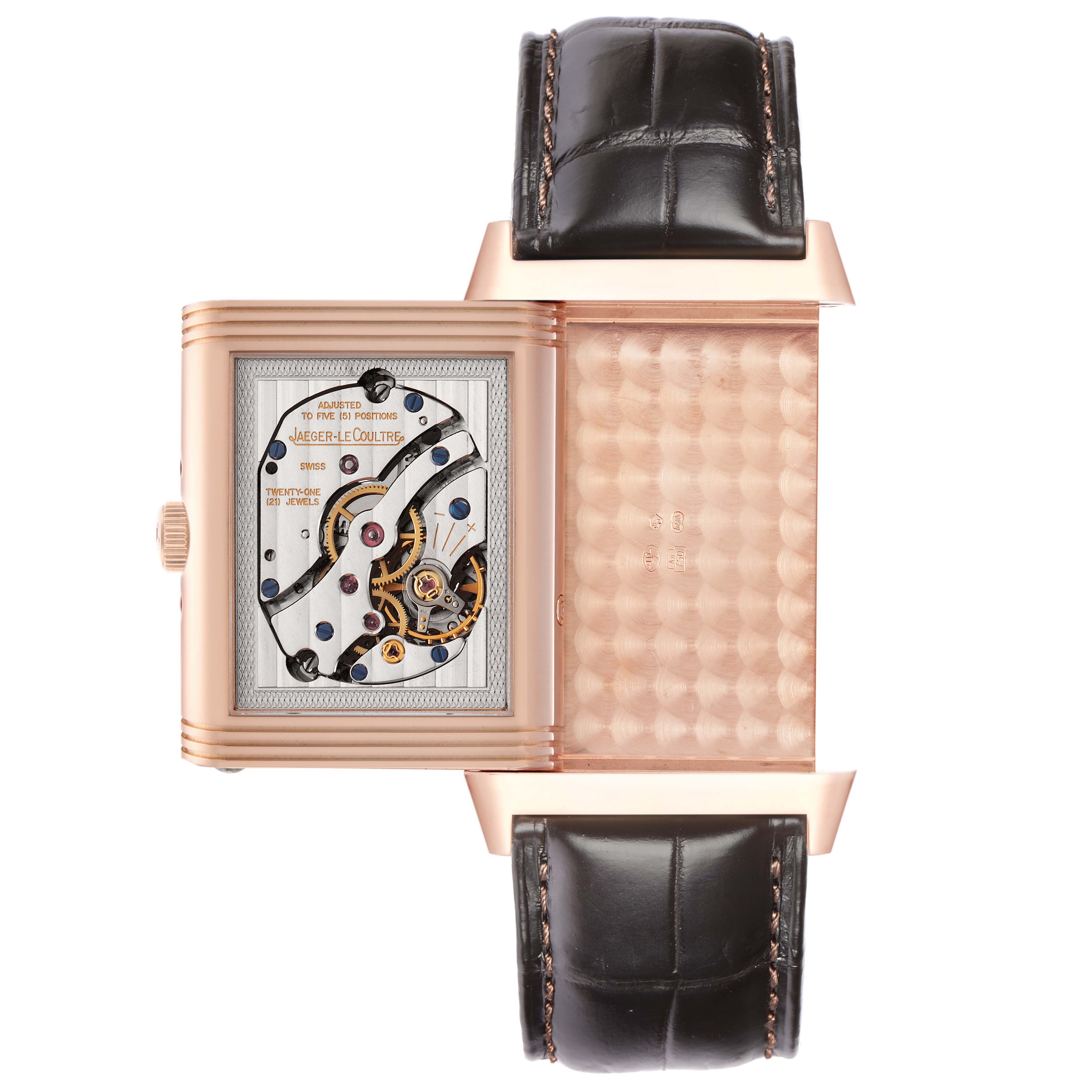 The Jaeger-LeCoultre Reverso watch is shown from above, displaying its open case and intricate movement details.