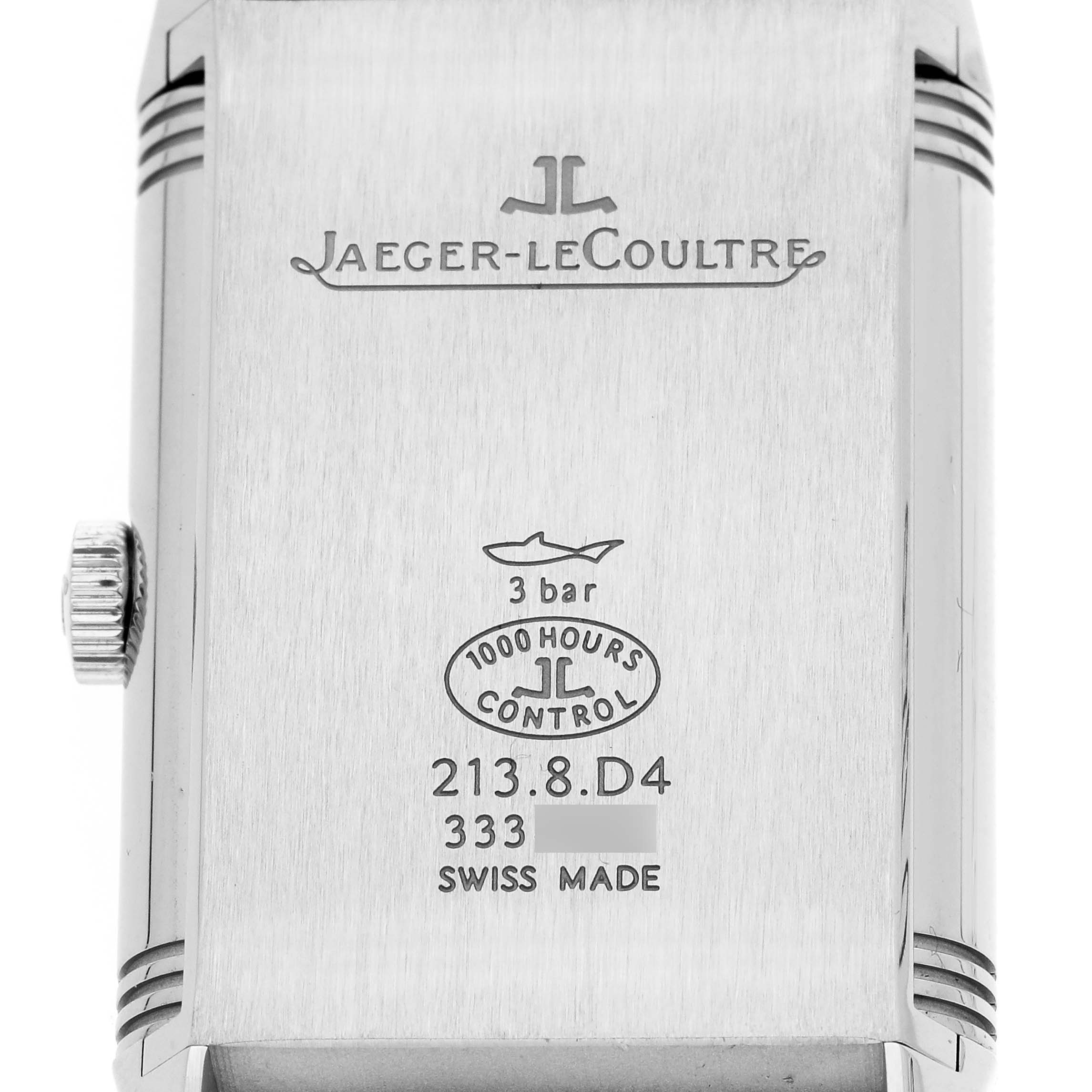 The image shows the back case of a Jaeger-LeCoultre Reverso watch, featuring brand engravings and a visible crown on the left side.