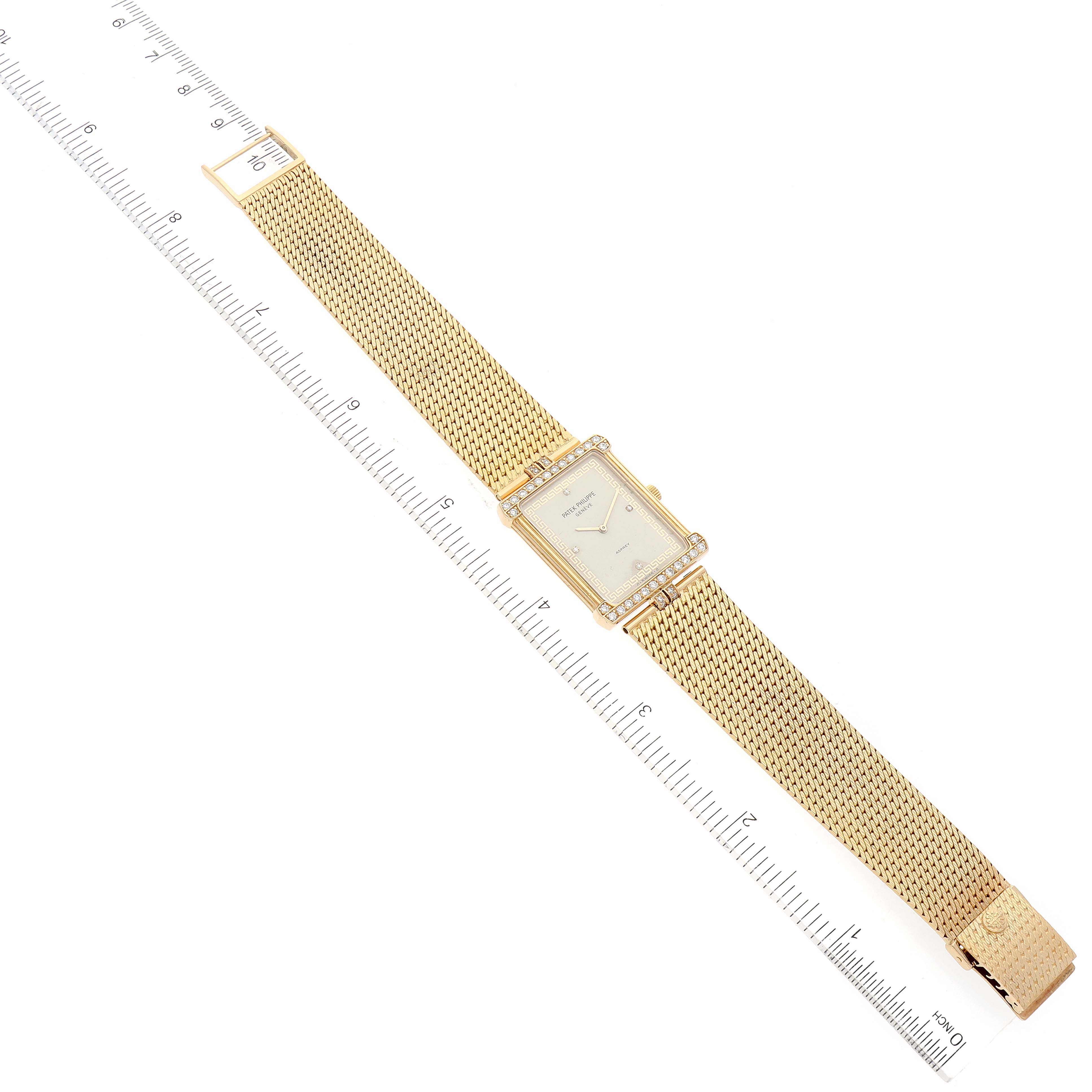 The Patek Philippe Gondolo 3776/2 Men's Yellow Gold Beige Dial 3776/2 Men's Yellow Gold Beige Dial watch is shown at a top-down angle, highlighting its rectangular dial and gold mesh strap, with a ruler for scale.