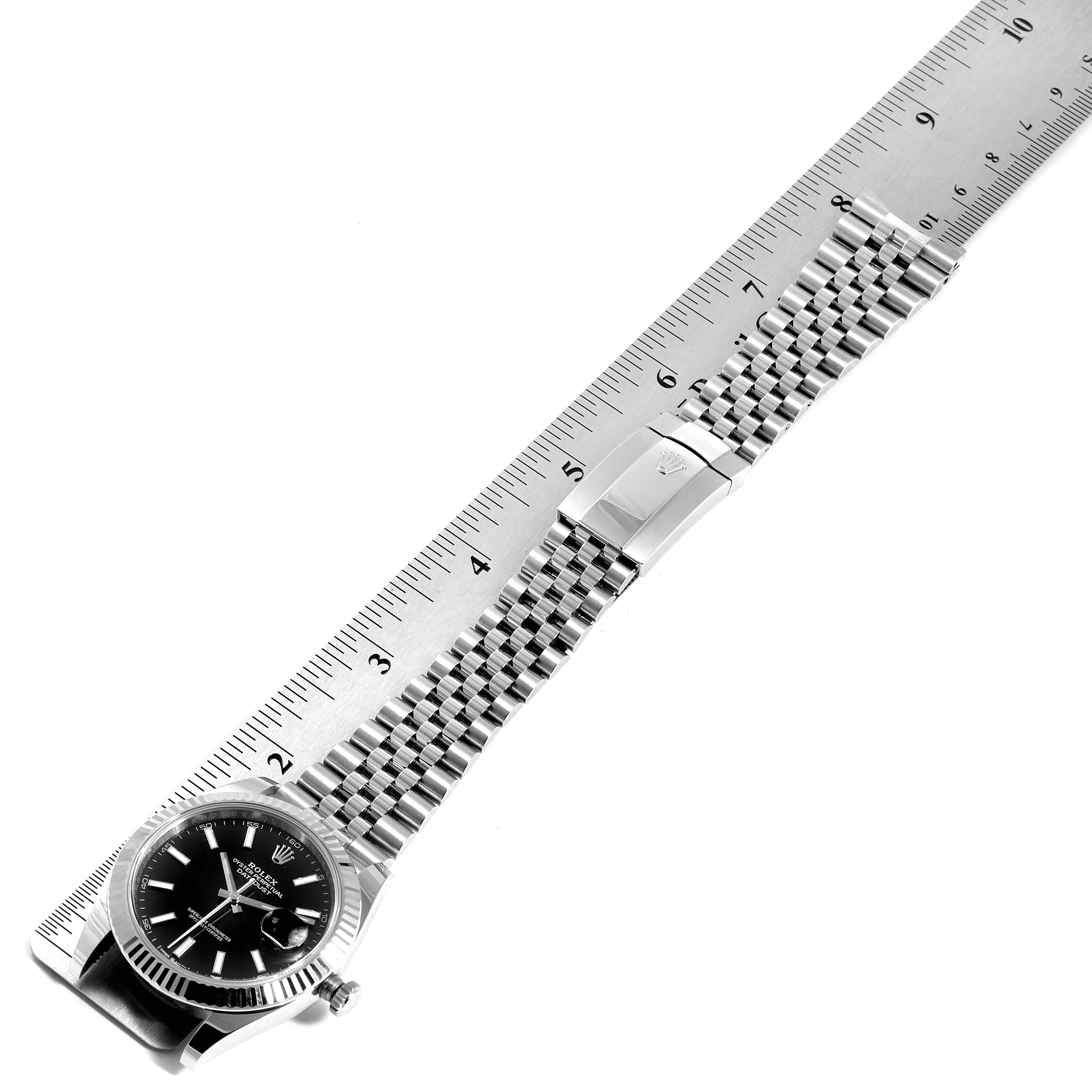 The Rolex Datejust 41 126334 Men
s Stainless Steel Black Dial 126334 Men
s Stainless Steel Black Dial watch is shown at a diagonal angle with its bracelet extended along a ruler for measurement.