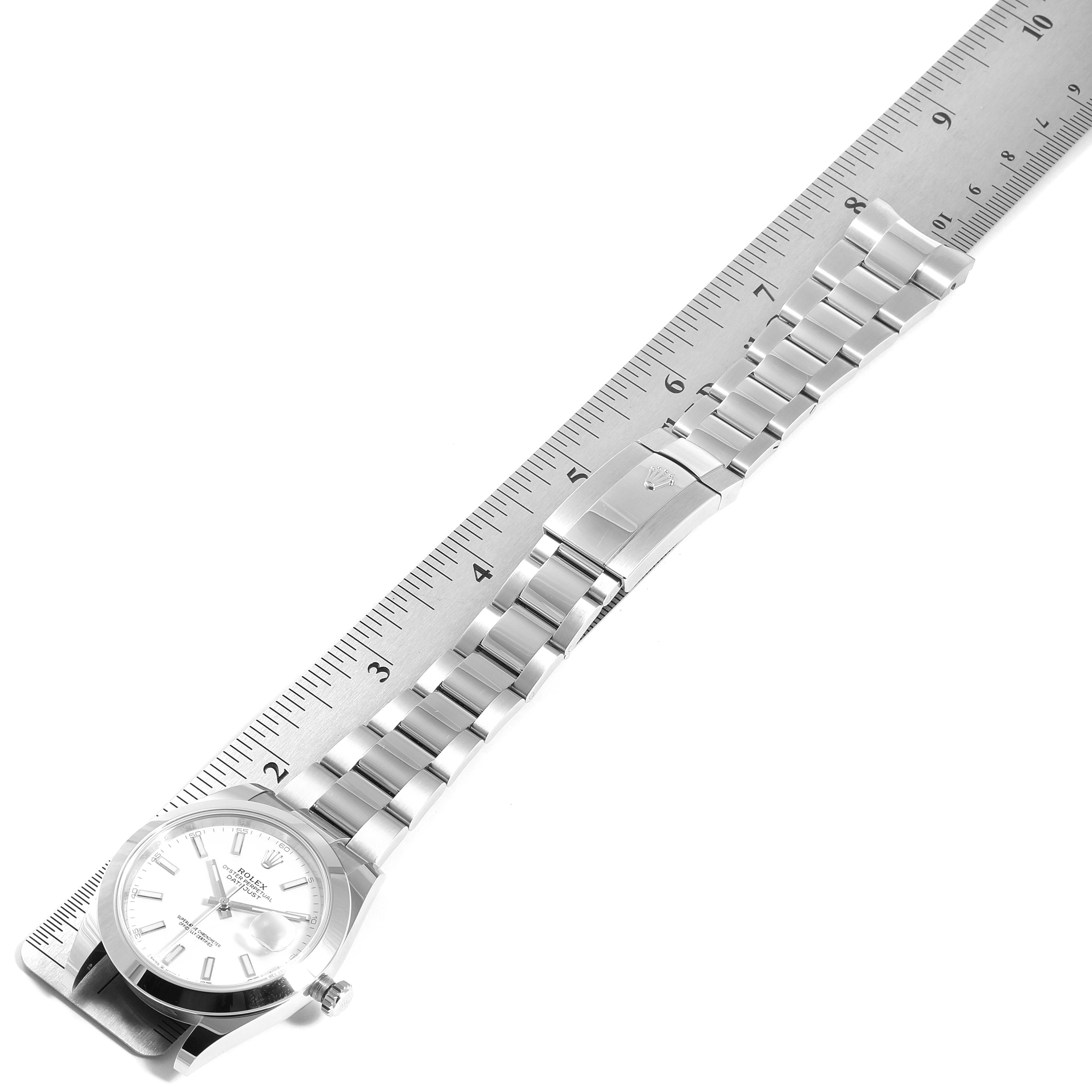 The Rolex Datejust 41 126300 Men's Stainless Steel White Dial 126300 Men's Stainless Steel White Dial watch is shown from a top-down angle, featuring its dial, bracelet, and clasp beside a ruler for scale.