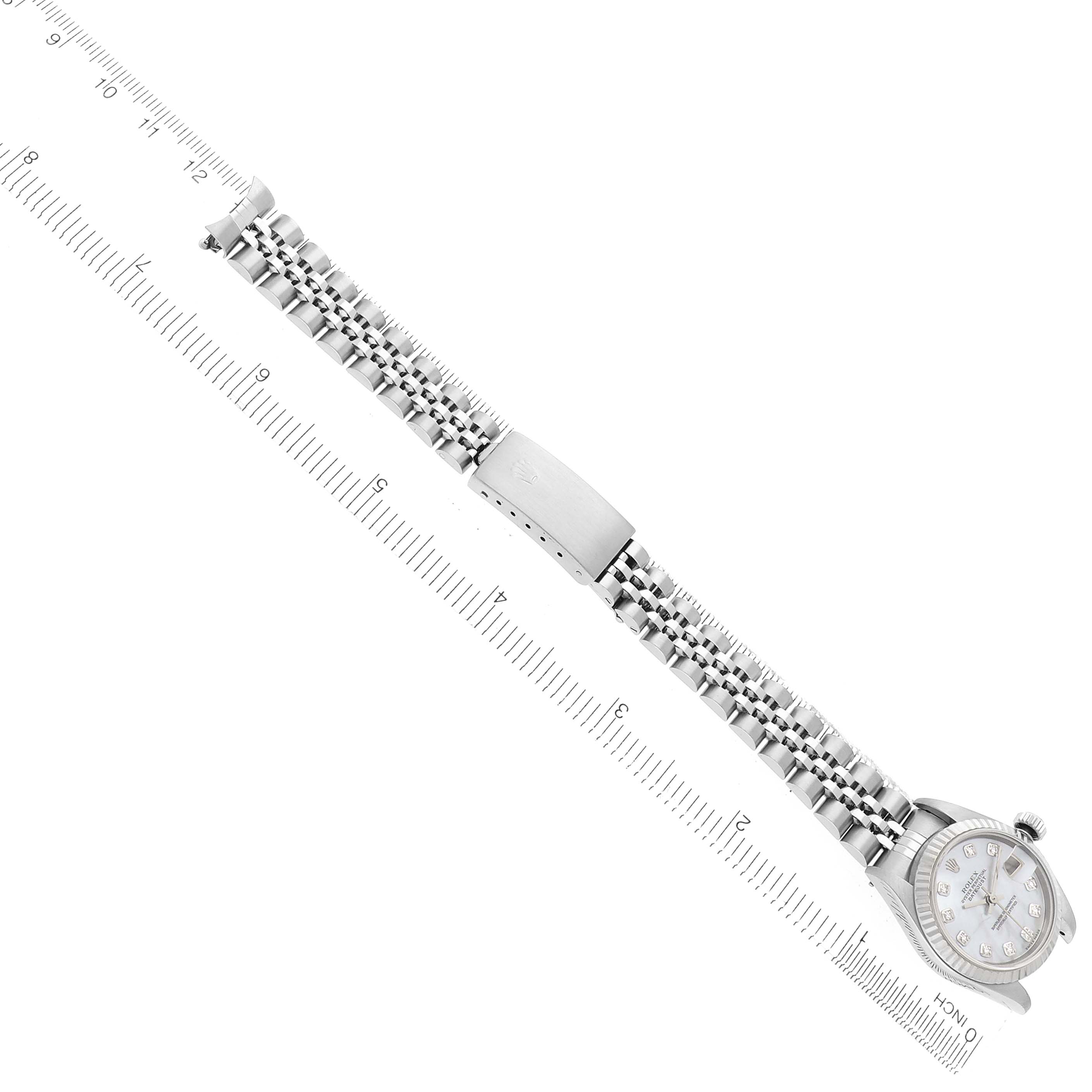 The Rolex Datejust 79174 Women
s Stainless Steel Mother of Pearl Dial watch is shown from a top-down angle, highlighting the bracelet, clasp, and face with a ruler for scale.