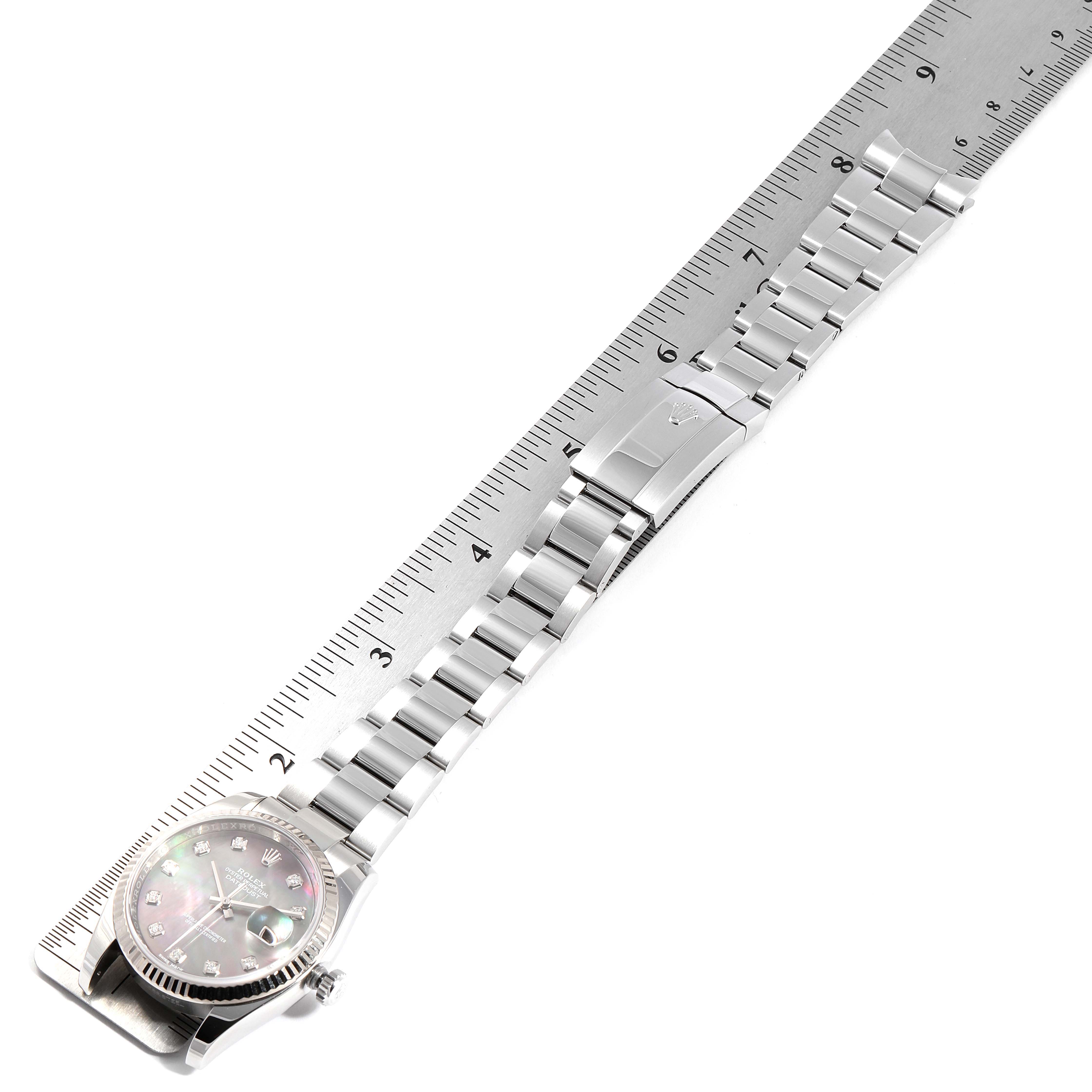 This image shows a Rolex Datejust 116234 Men
s Stainless Steel Mother of Pearl Dial 116234 Men
s Stainless Steel Mother of Pearl Dial watch set alongside a ruler, displaying the watch face, strap, and clasp.