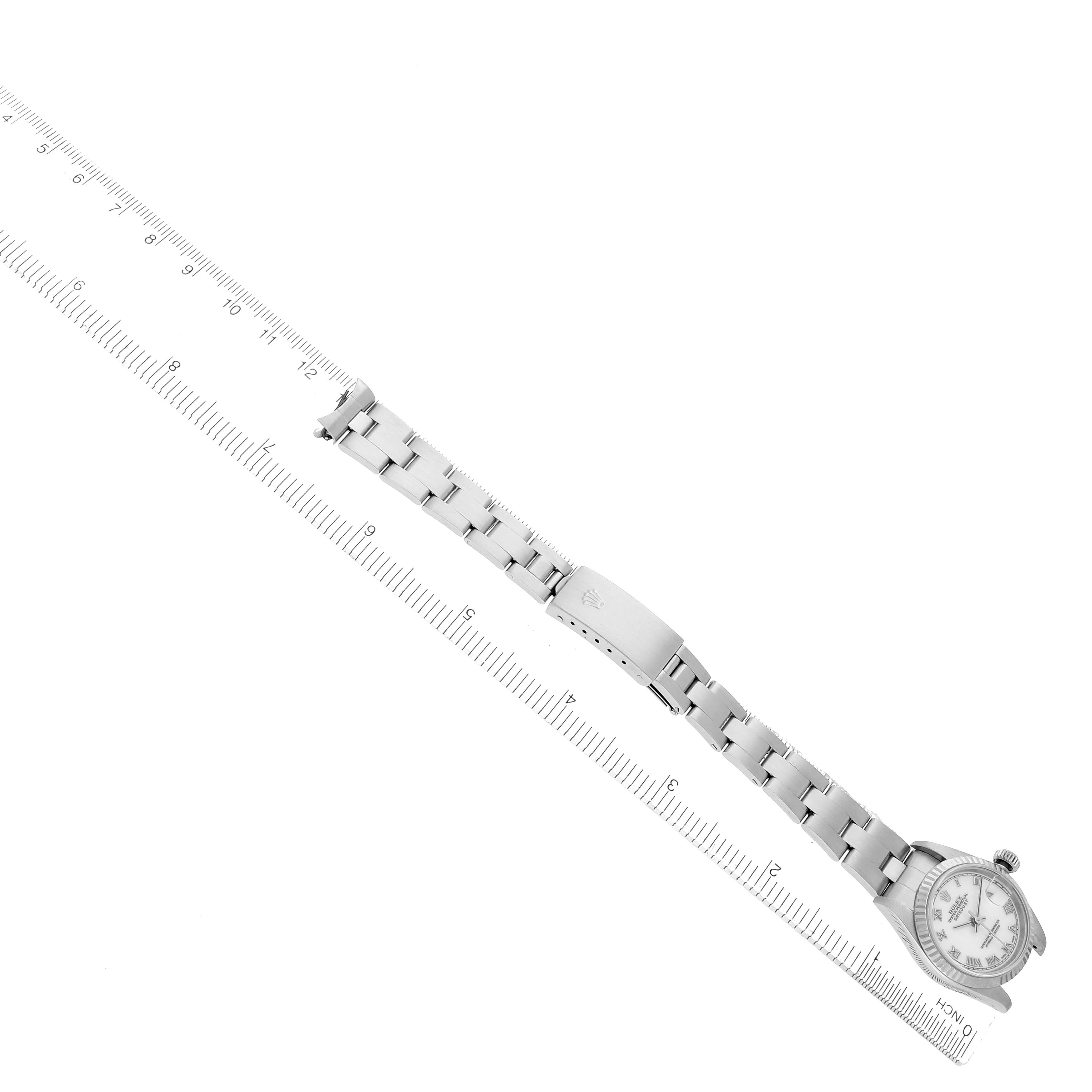 The Rolex Datejust 79174 Women
s Stainless Steel White Dial watch is shown at an angle displaying its full bracelet with the dial slightly angled, accompanied by a ruler.