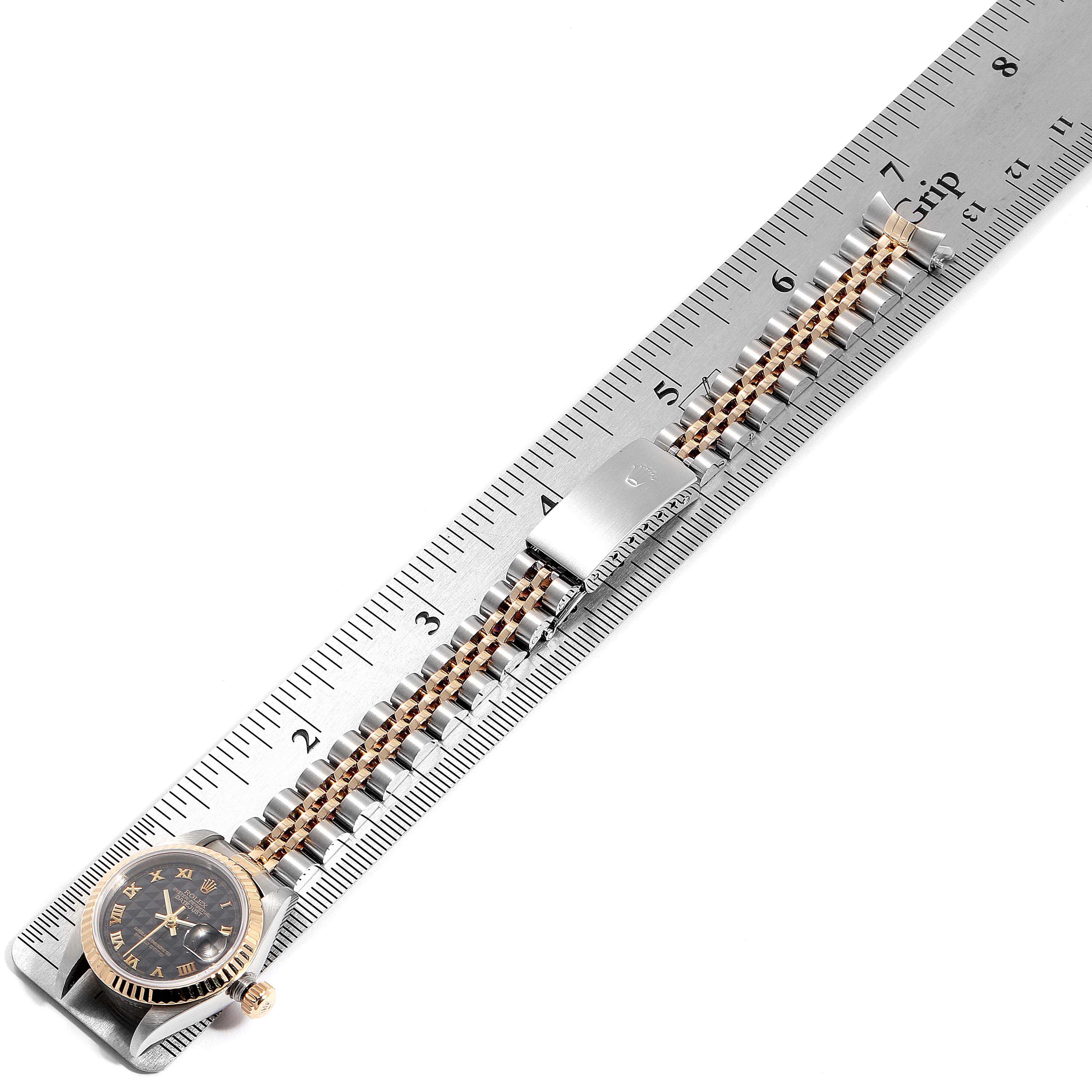 The Rolex Datejust 79173 Women's Steel and Gold (two tone) Black Dial 79173 Women's Steel and Gold (two tone) Black Dial watch is shown laid flat beside a ruler, displaying the face, bracelet, and clasp.