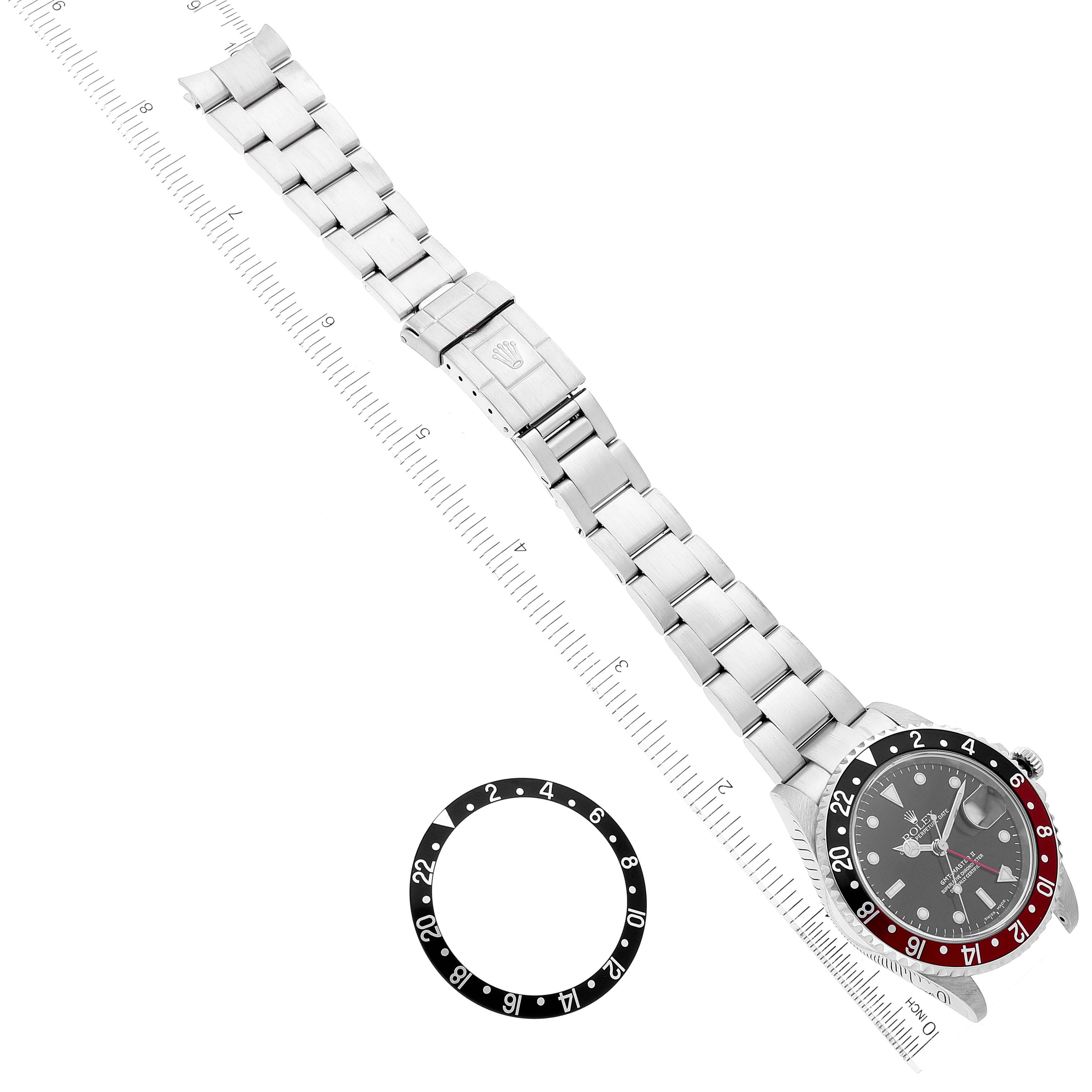 The image shows a top-down view of a Rolex GMT-Master 16710 Men
s Stainless Steel Black Dial 16710 Men
s Stainless Steel Black Dial watch, its bracelet, and a separate bezel insert with measurement rulers.