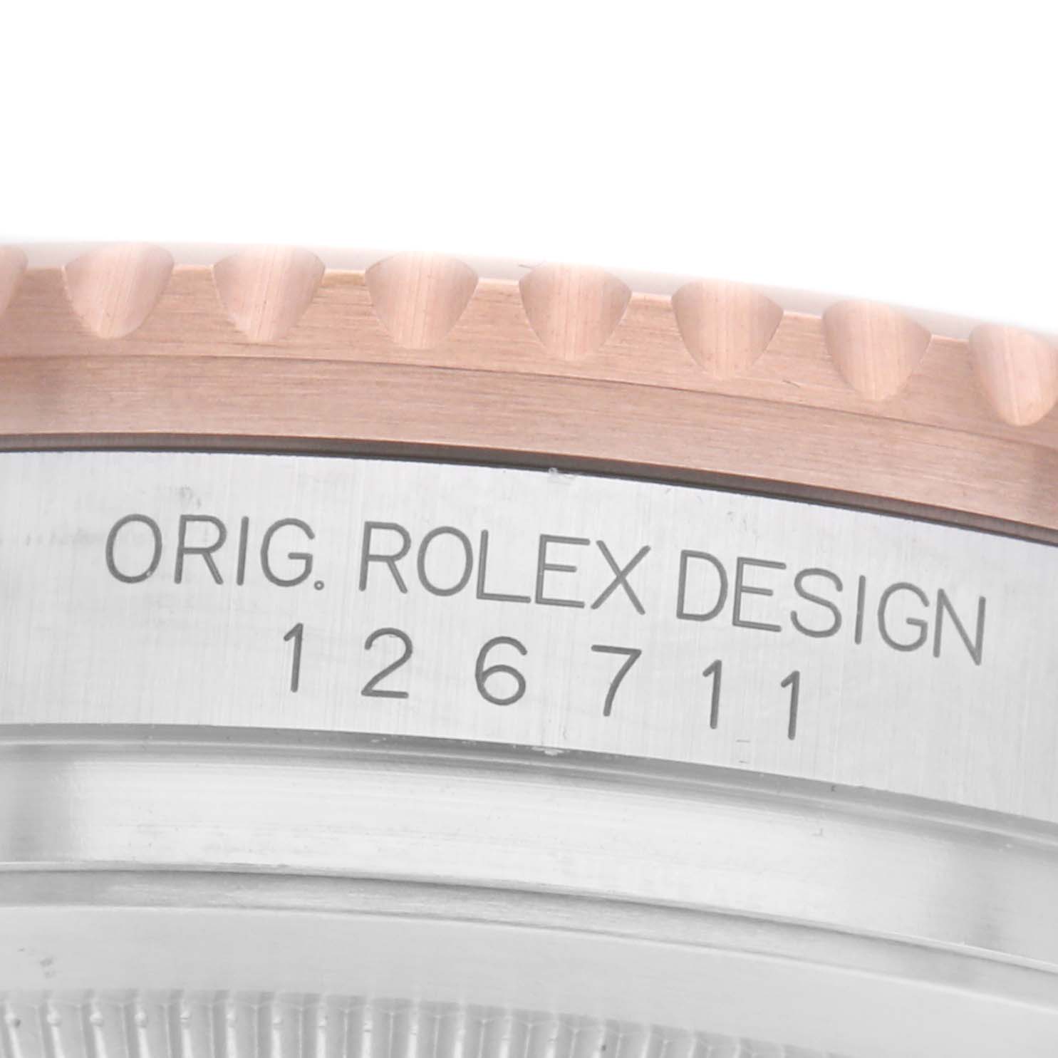 The image shows a close-up of the Rolex GMT-Master 126711 Men
s Steel and Gold (two tone) Black Dial bezel and case with the model number 126711 engraved.