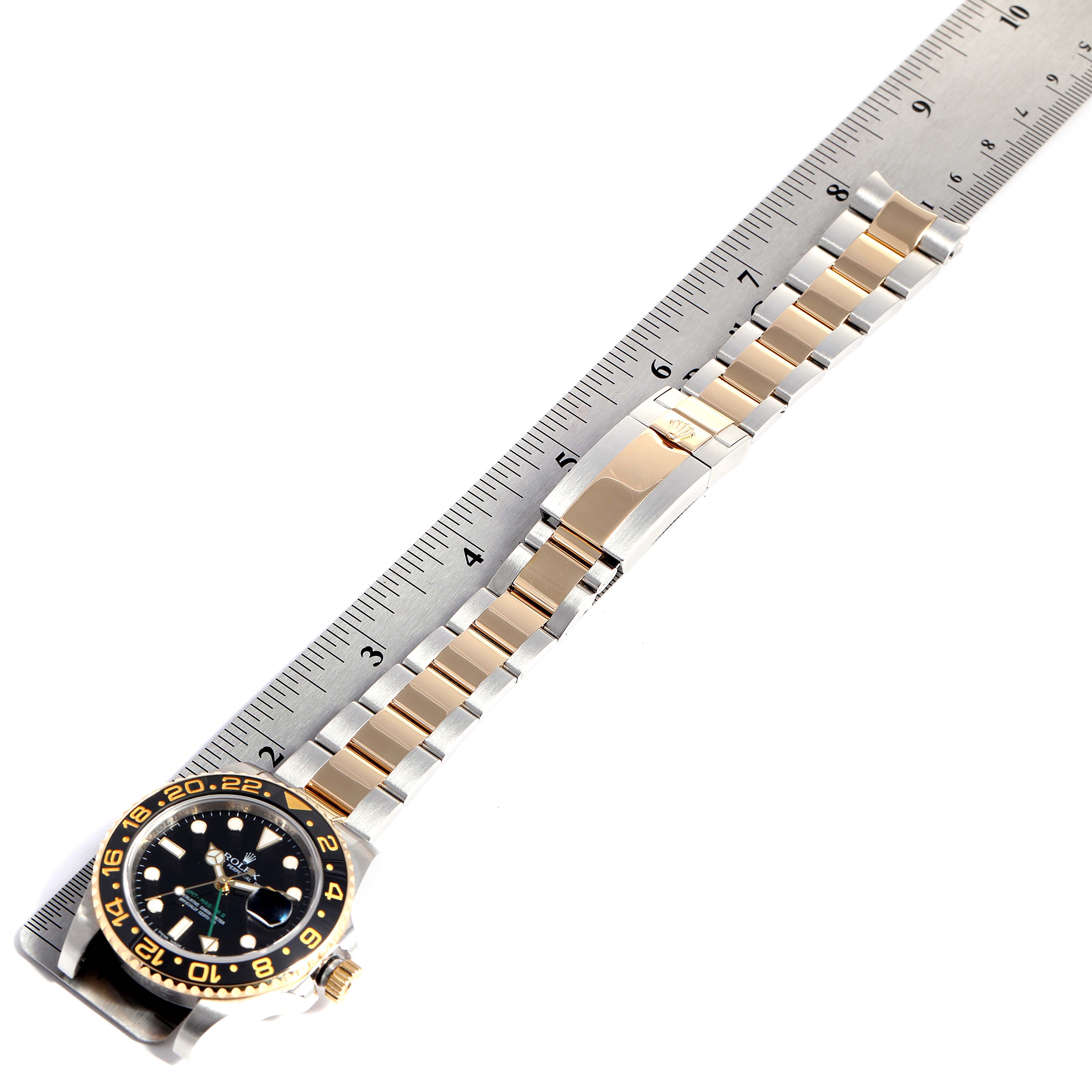 The image shows a Rolex GMT-Master 116713 Men's Steel and Gold (two tone) Black Dial 116713 Men's Steel and Gold (two tone) Black Dial watch laid flat, aligned with a ruler to measure its length.