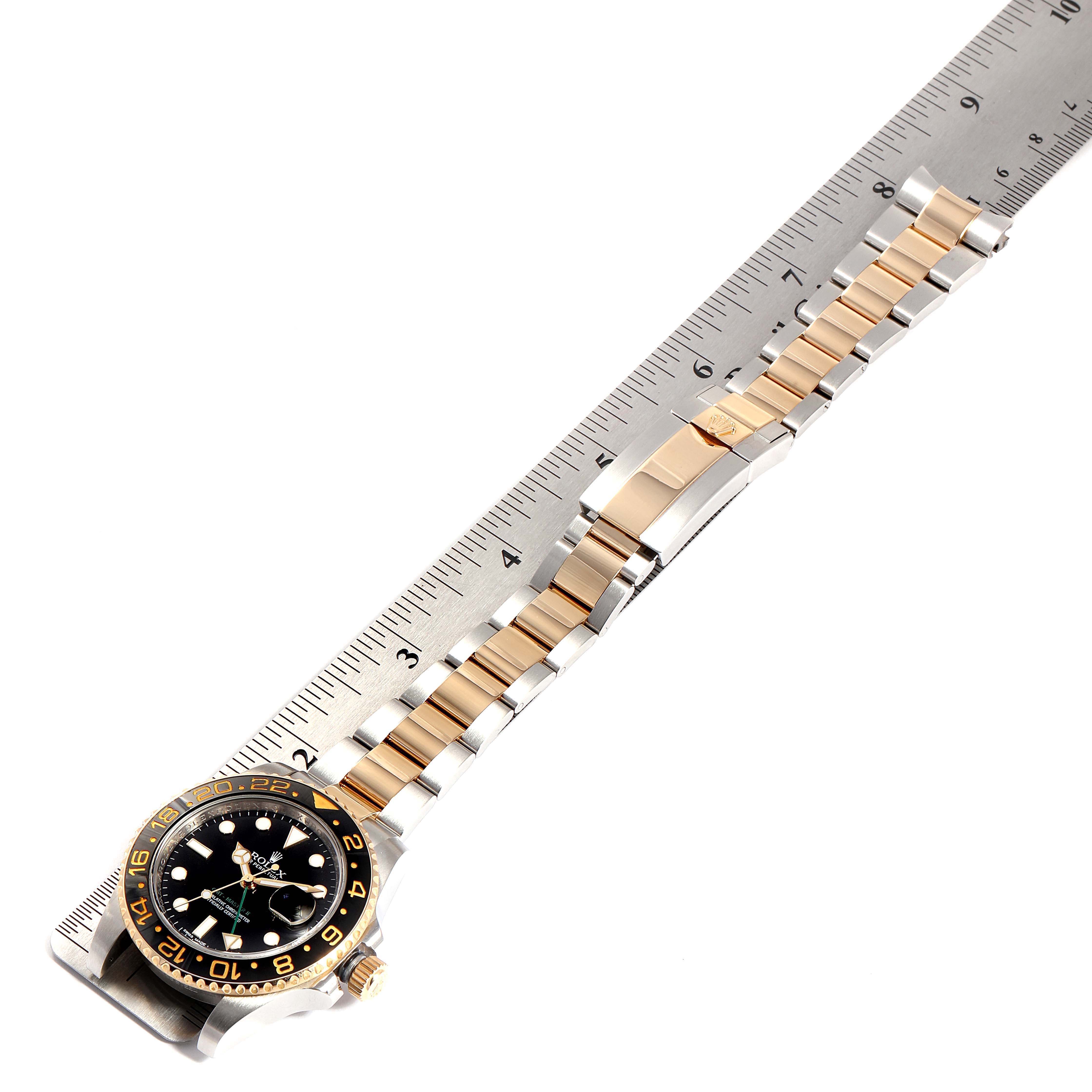 This image shows a Rolex GMT-Master 116713 Men
s Stainless Steel Black Dial 116713 Men
s Stainless Steel Black Dial watch laid flat next to a ruler, displaying its bracelet and face.