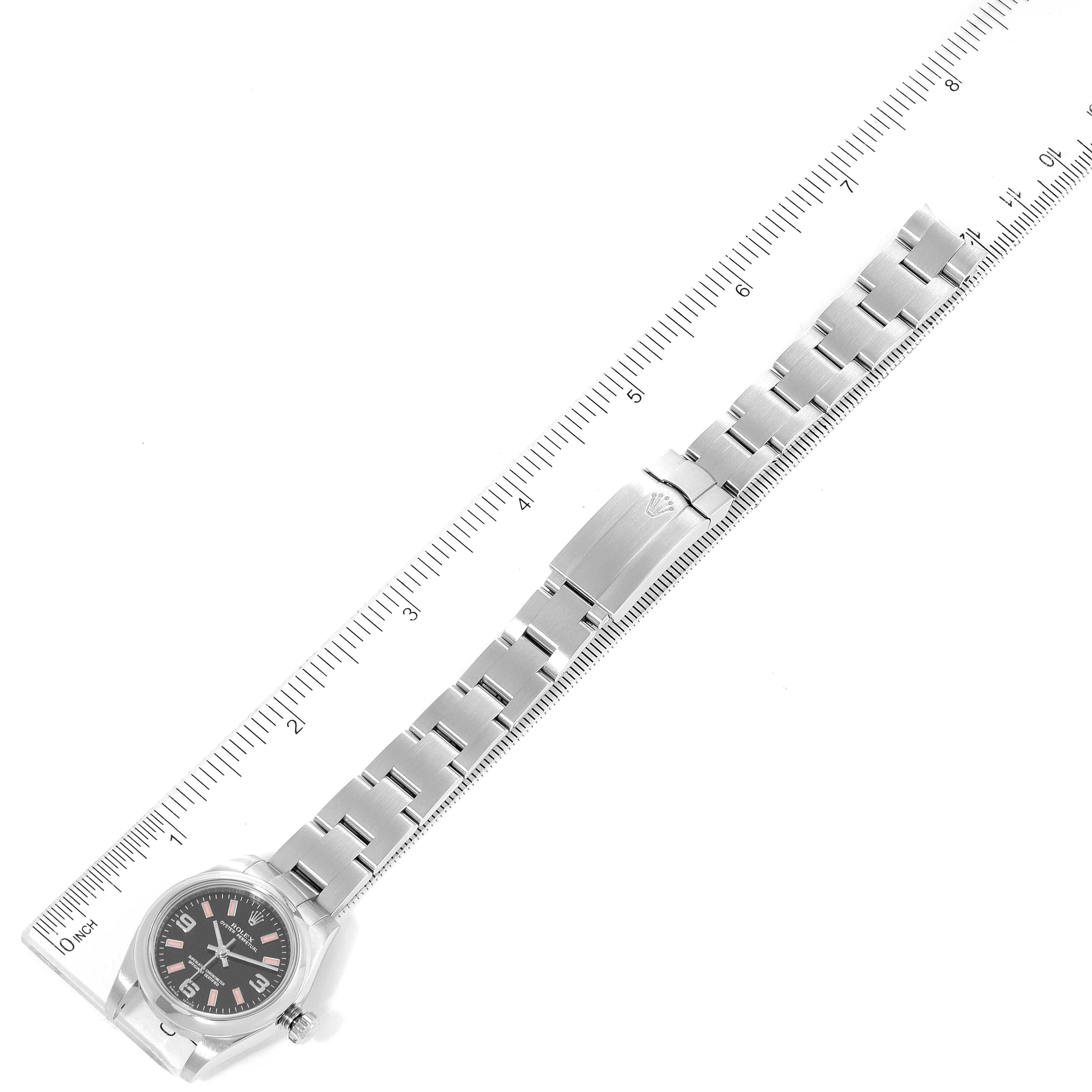 The image shows a top-down view of a Rolex Oyster Perpetual 176200 Women's Stainless Steel Black Dial 176200 Women's Stainless Steel Black Dial watch, including the face and metal bracelet with clasp, alongside a ruler.