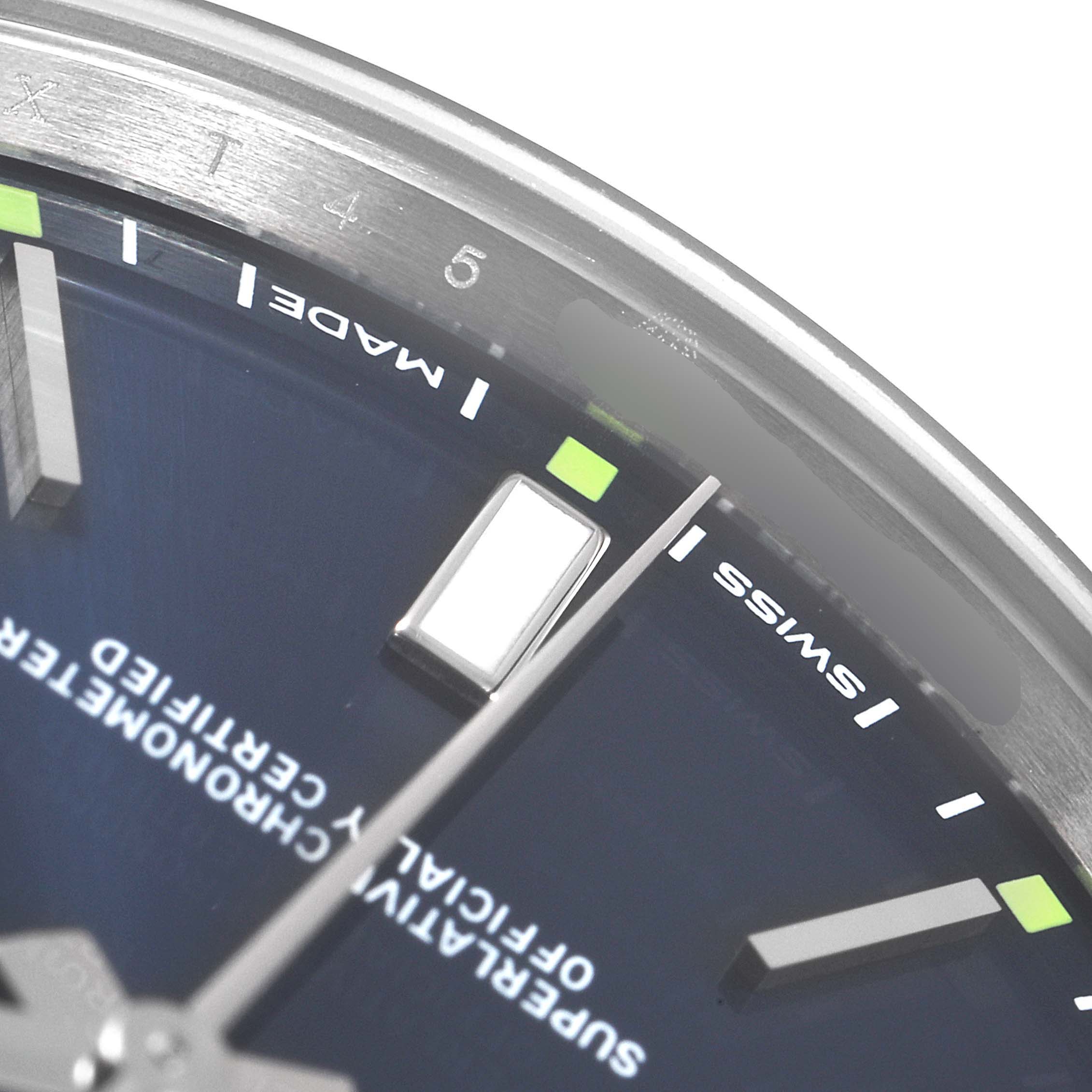 This close-up of a Rolex Oyster Perpetual 114300 Men's Stainless Steel Blue Dial 114300 Men's Stainless Steel Blue Dial watch shows part of the blue dial, hour indices, minute markers, and part of the hands.