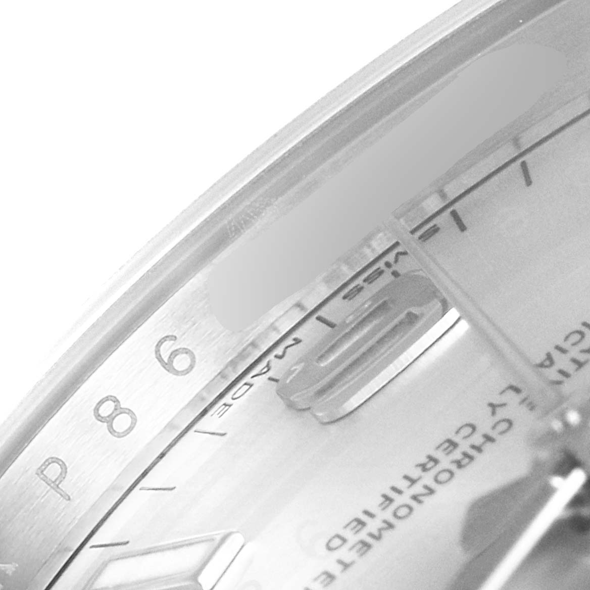This close-up image of the Rolex Oyster Perpetual 114200 Men's Stainless Steel Silver Dial 114200 Men's Stainless Steel Silver Dial watch shows the dial at an angle, highlighting part of the numbers and text.