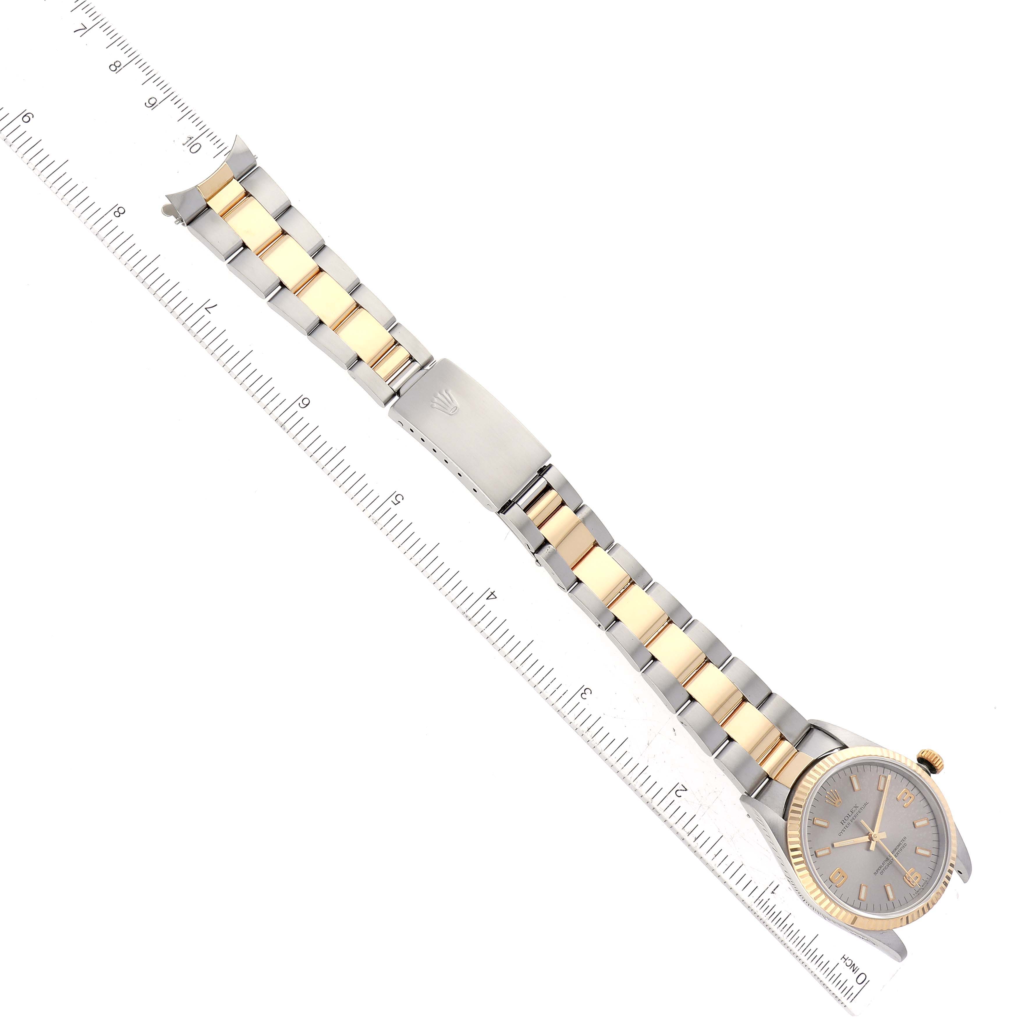 This image shows a Rolex Oyster Perpetual 14233 Men's Steel and Gold (two tone) Silver Dial 14233 Men's Steel and Gold (two tone) Silver Dial watch laid flat alongside a ruler, highlighting its bracelet and clasp.