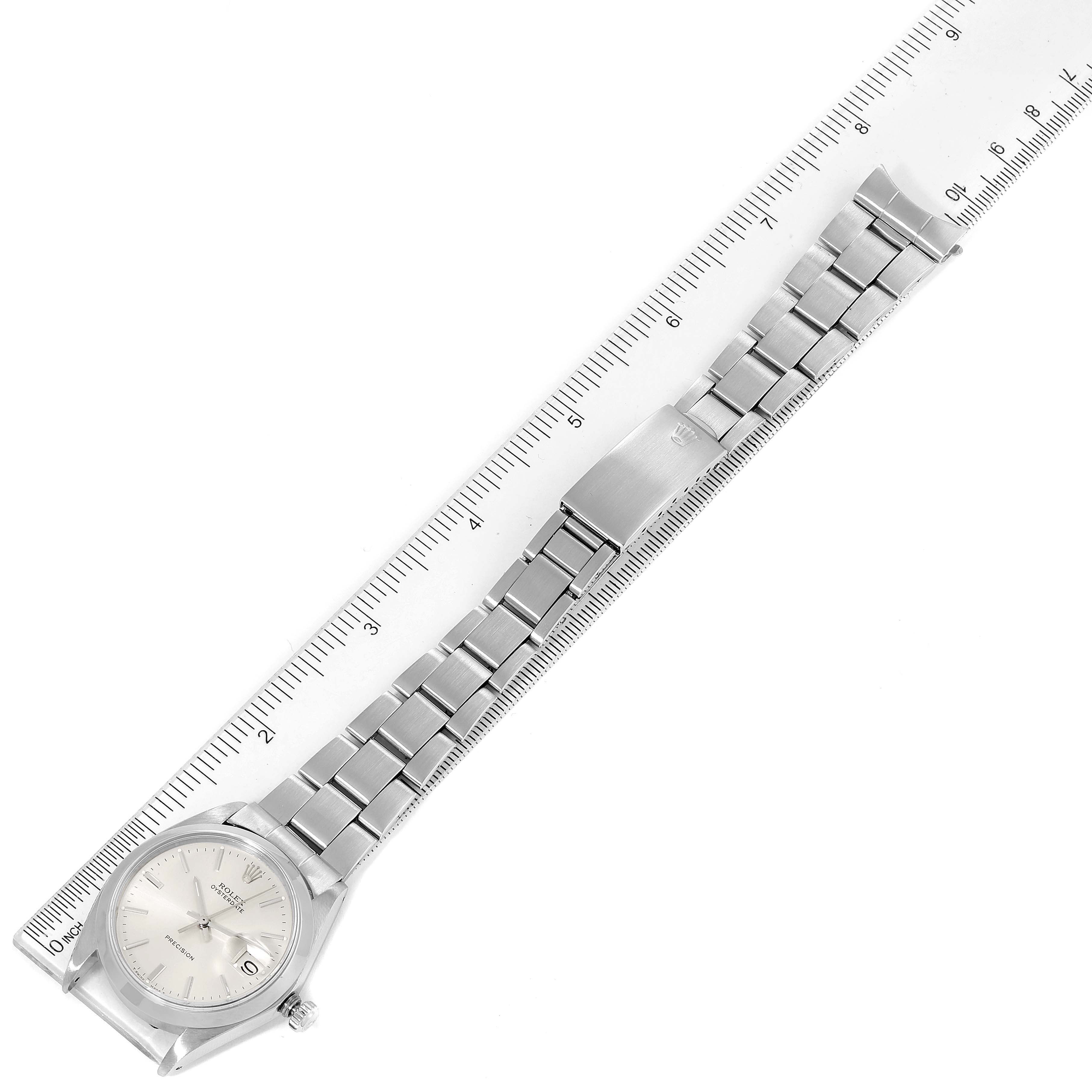 The image shows a top-down view of a Rolex Date 6694 Men's Stainless Steel Silver Dial 6694 Men's Stainless Steel Silver Dial model watch, featuring the dial, case, and full bracelet next to a ruler.
