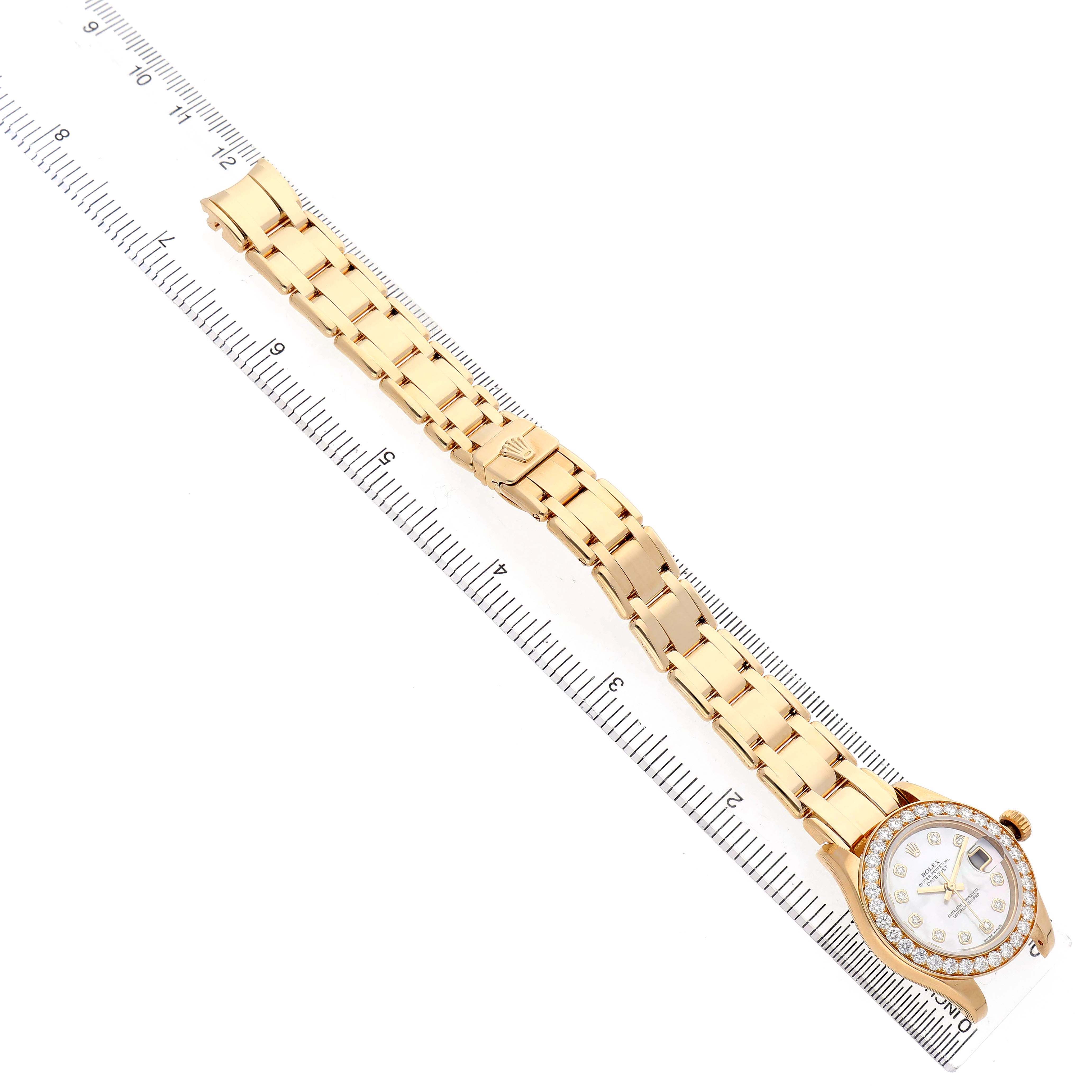 The Rolex Pearlmaster 80298 Women's Yellow Gold Mother of Pearl Dial watch is shown at an elevated angle, displaying the watch face, bracelet, and clasp alongside a ruler for scale.