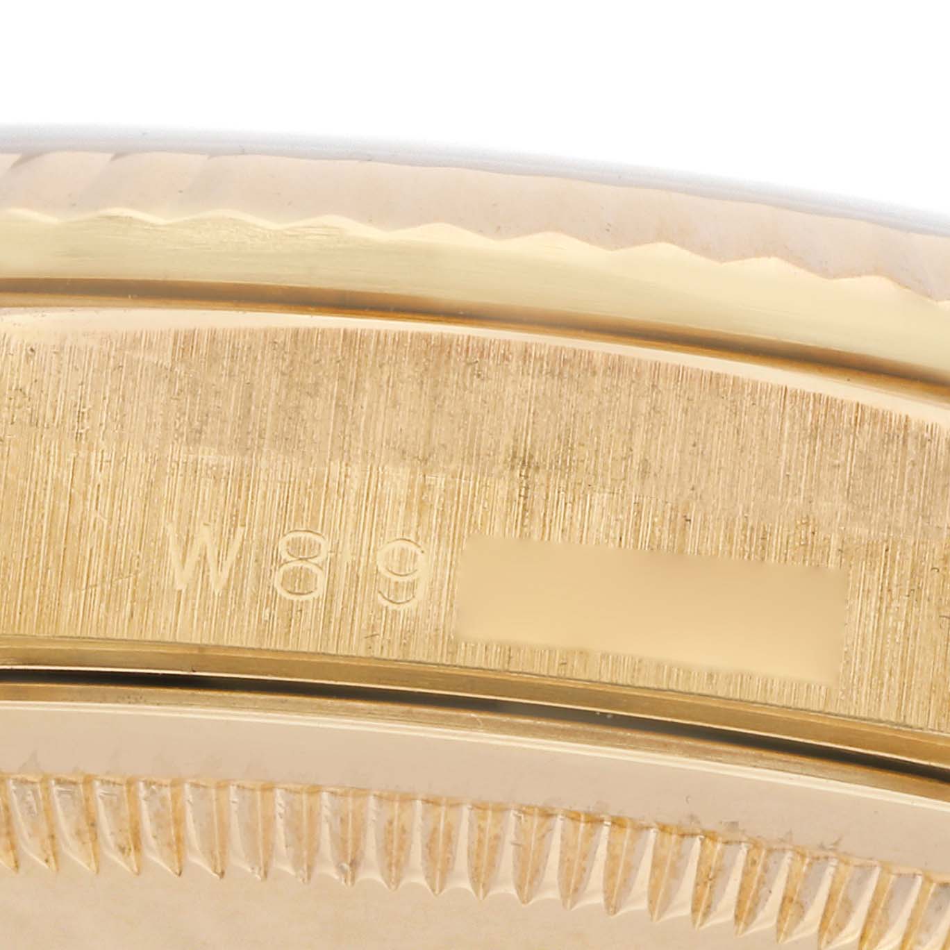 The image shows a close-up of the side of a Rolex President 18238 Men
s Yellow Gold Champagne Dial watch, highlighting the fluted bezel and engraved serial number on the case.