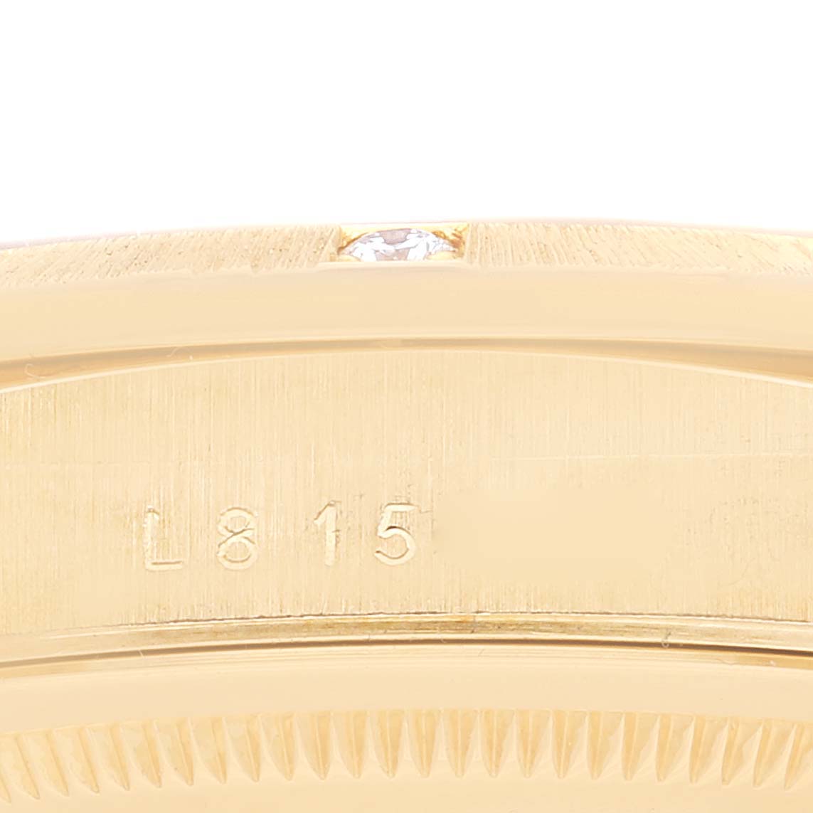 This is a close-up image of the side of a Rolex President 18308 Men's Yellow Gold Champagne Dial 18308 Men's Yellow Gold Champagne Dial watch, showing the serial number and part of the bezel with a small diamond.