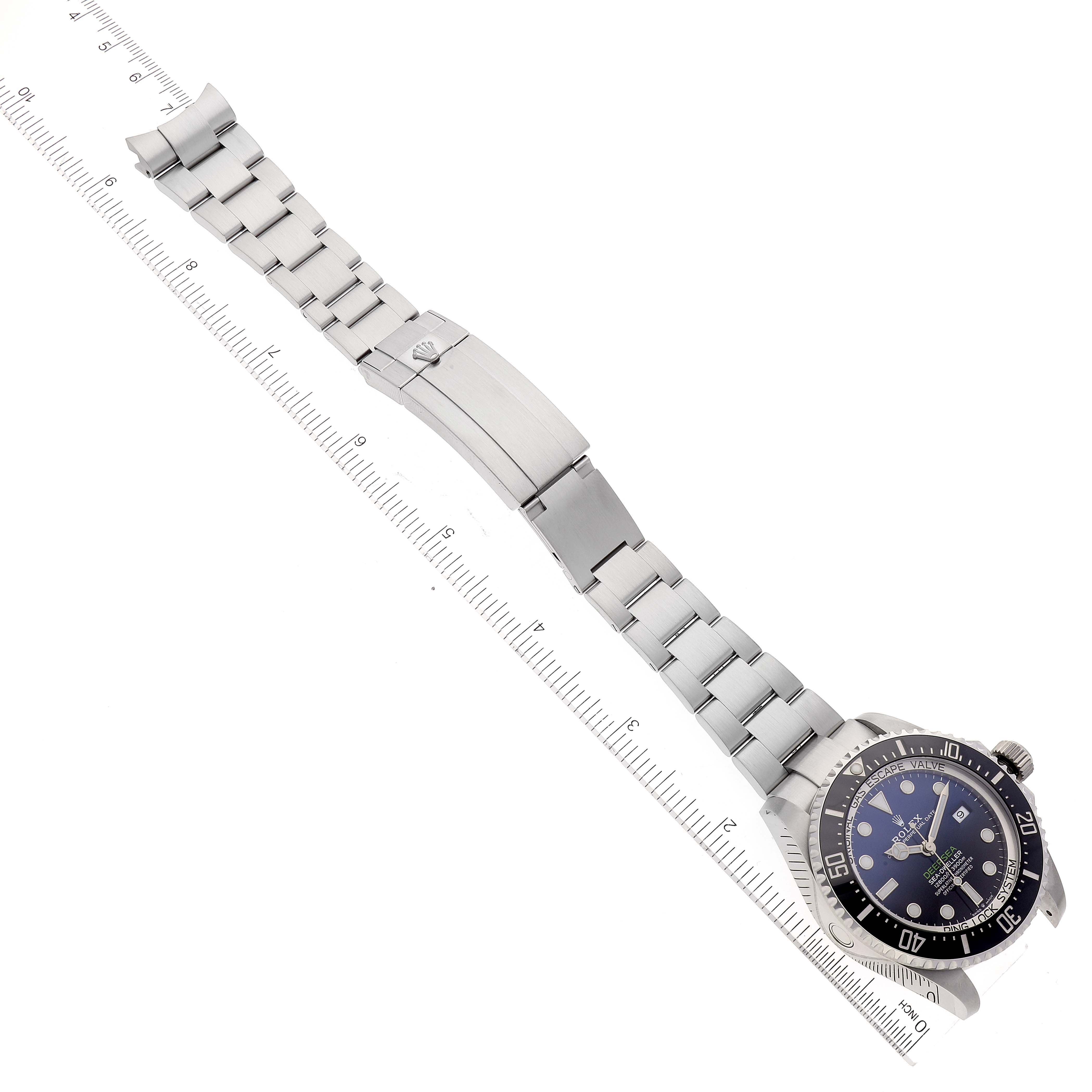 The image shows a Rolex Sea-Dweller 126660 Men
s Stainless Steel Blue Dial 126660 Men
s Stainless Steel Blue Dial watch and its stainless steel bracelet laid out flat with a ruler for scale.