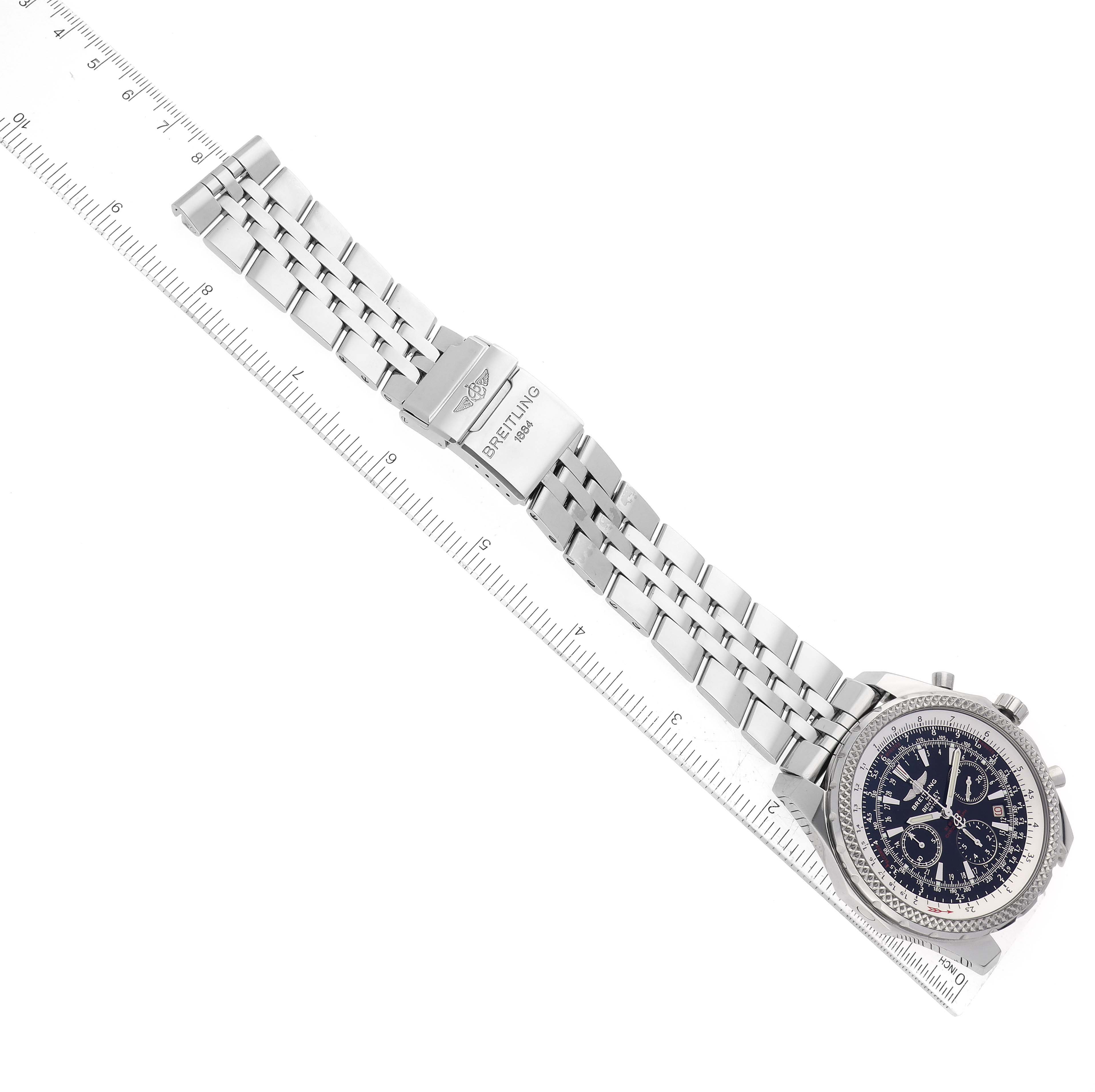 The Bentley model by Breitling is shown at an angled top view, displaying the watch face, band, clasp, and part of a measuring scale.