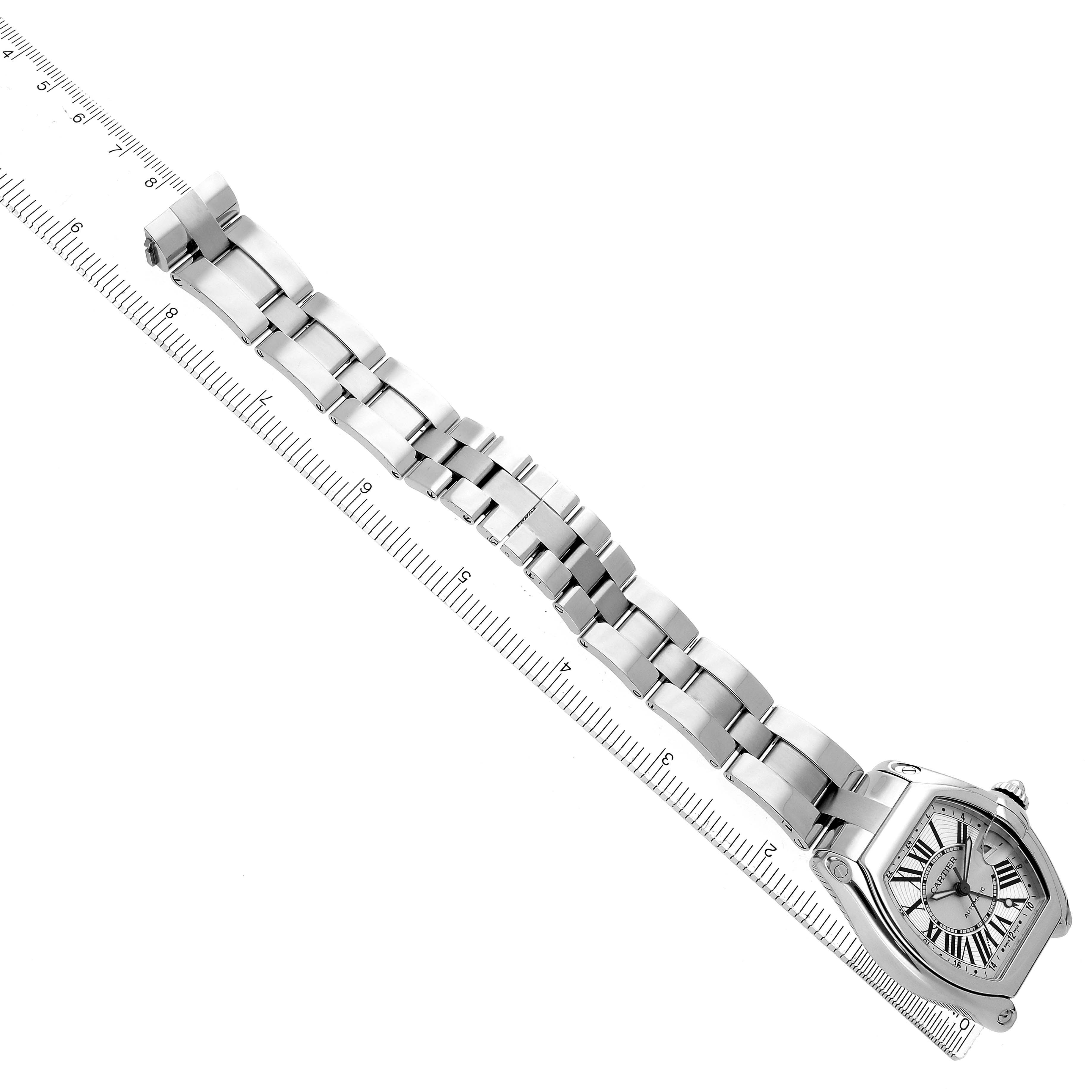 The Cartier Roadster W62032X6 Men
s Stainless Steel Silver Dial watch is angled diagonally, showing its face, bracelet, and part of a ruler for scale.