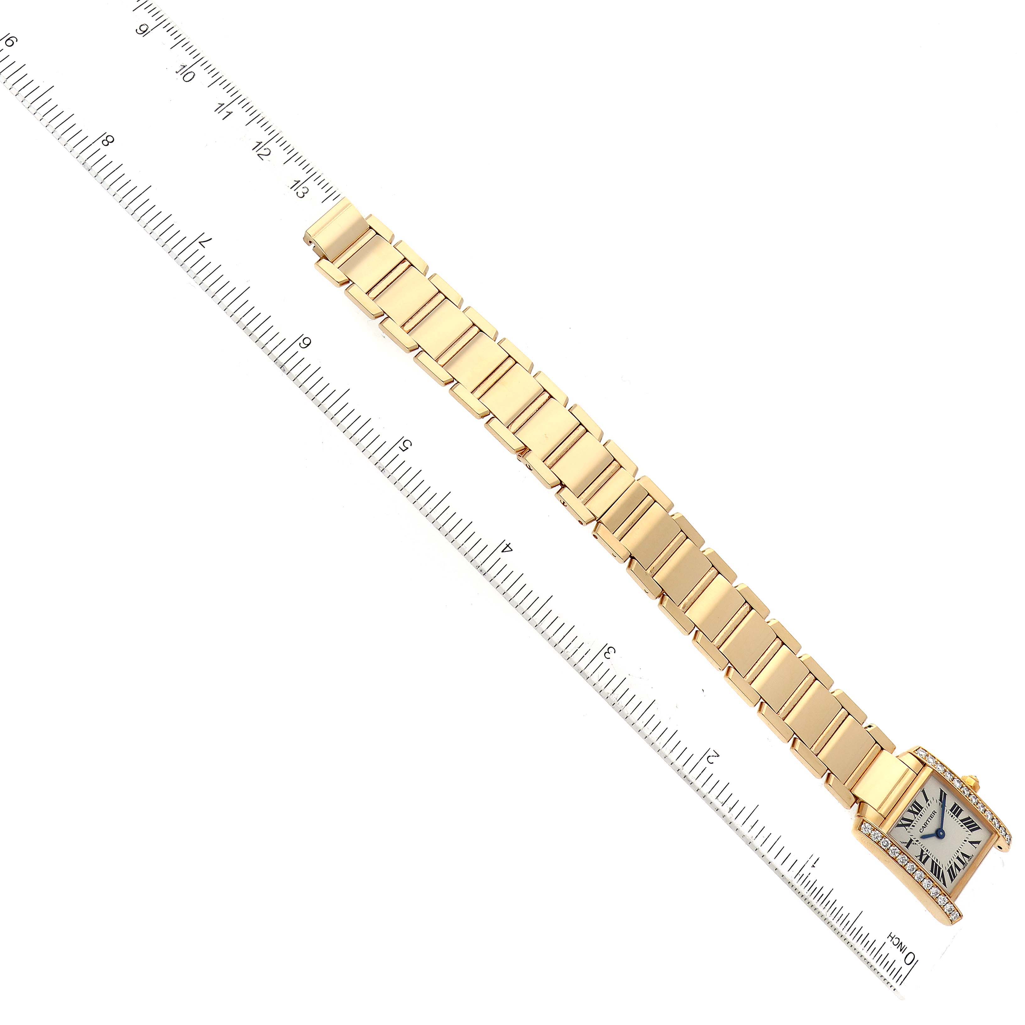 The Cartier Tank Francaise WE1001R8 Women's Yellow Gold Silver Dial WE1001R8 Women's Yellow Gold Silver Dial watch is shown from a top-down angle with a ruler for scale, displaying the bracelet and face.