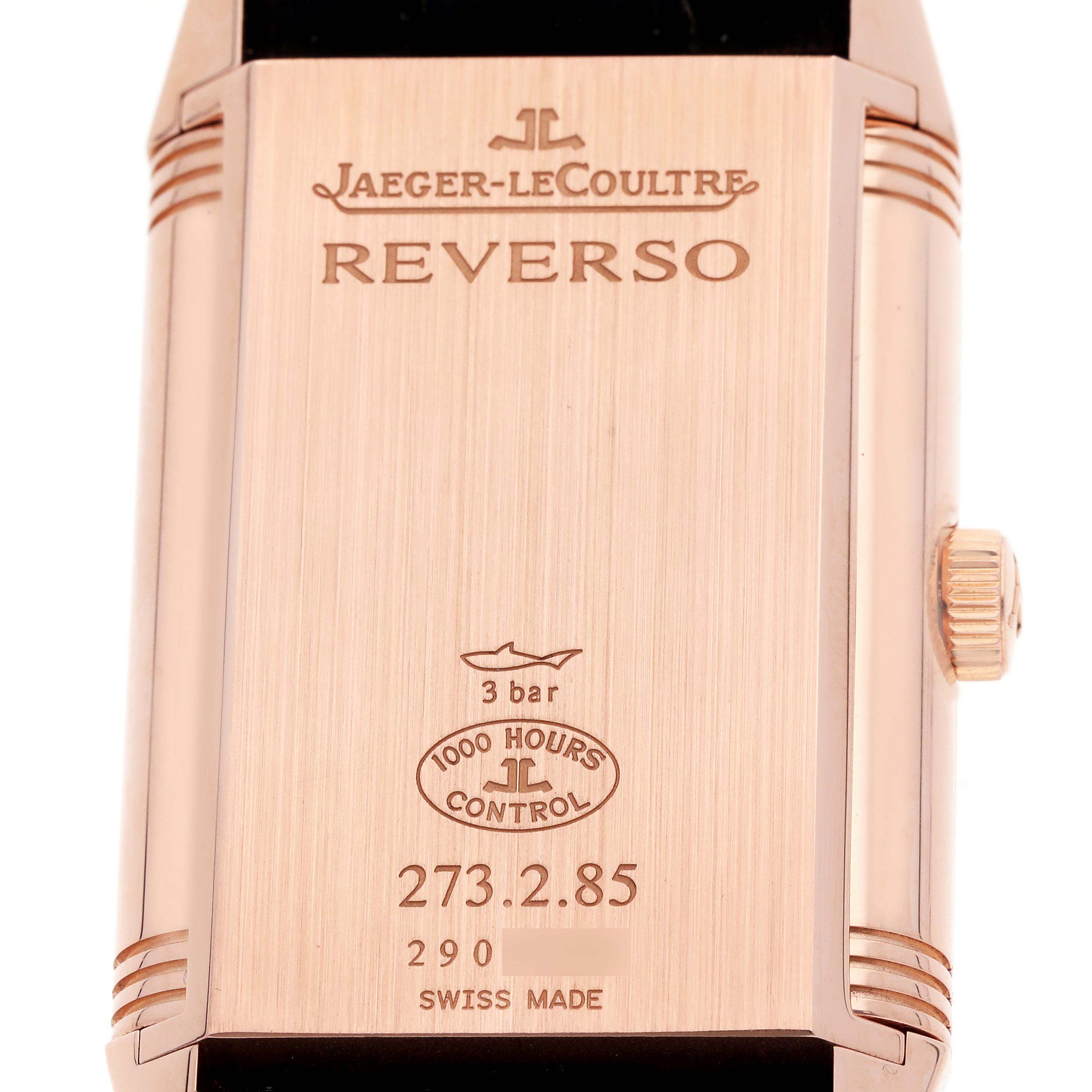 The image shows the back of a Jaeger-LeCoultre Reverso watch, including engravings, brand logo, and crown.