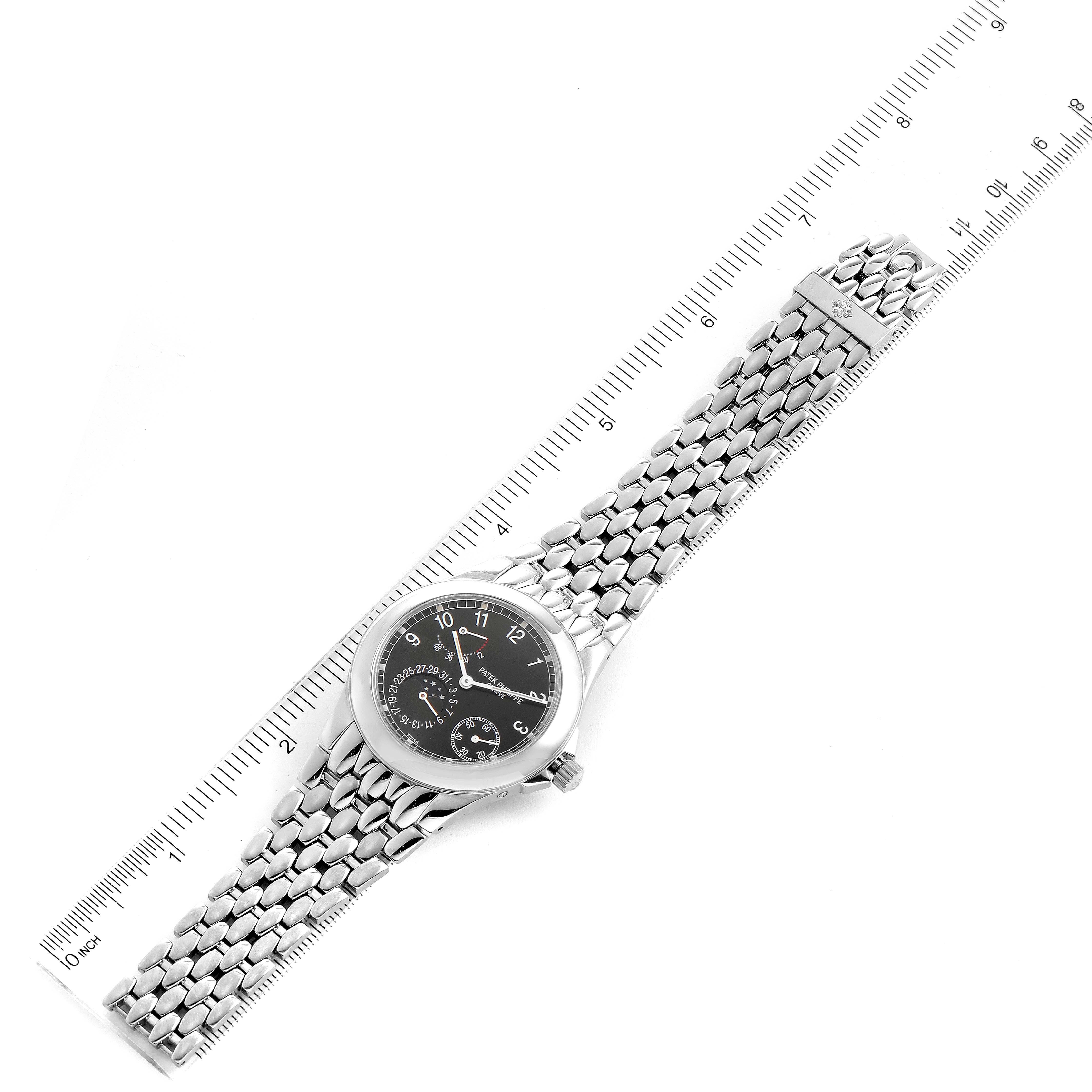 The image displays a Patek Philippe Neptune 5085A/1A-001 Men's Stainless Steel Black Dial 5085A/1A-001 Men's Stainless Steel Black Dial watch laid flat next to a ruler, capturing the watch face, case, and metal bracelet.